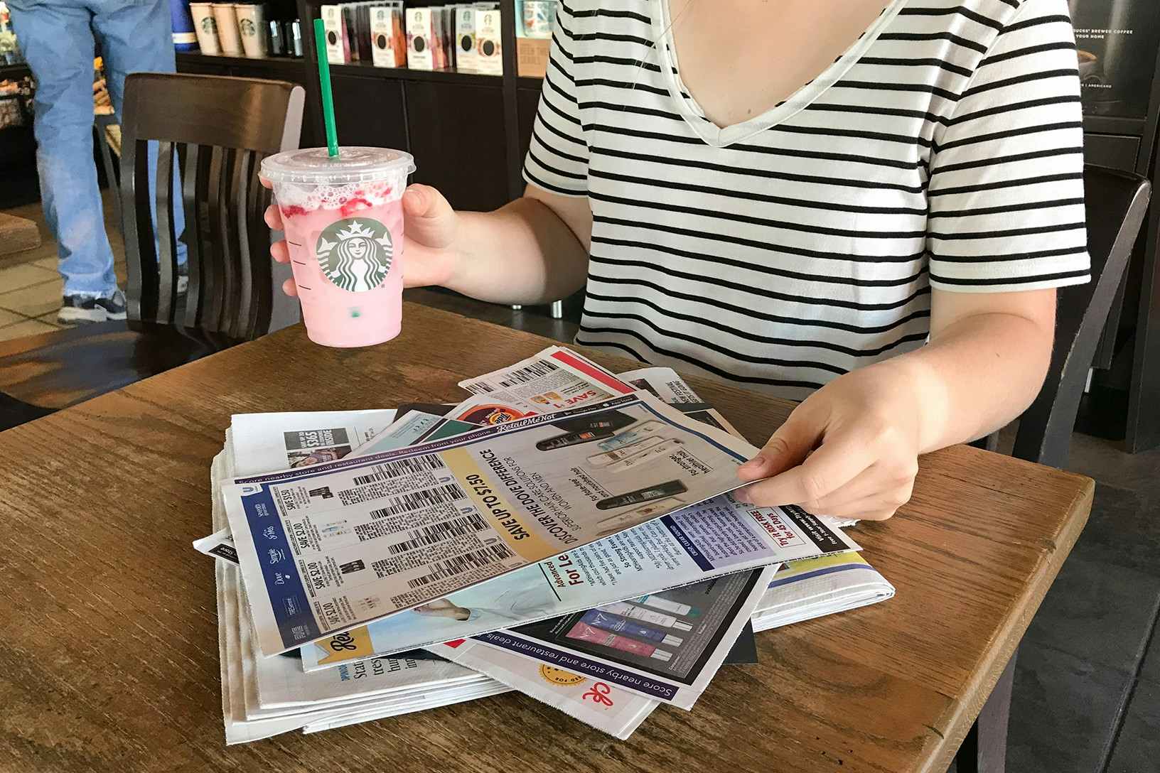 someone grabbing paper and starbucks drink in starbucks at a table