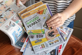 Woman going through newspaper coupon insert