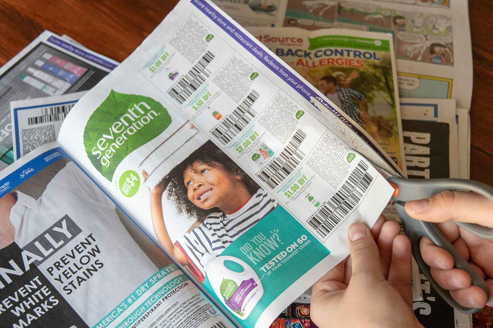 Person using scissors to cut newspaper coupon.