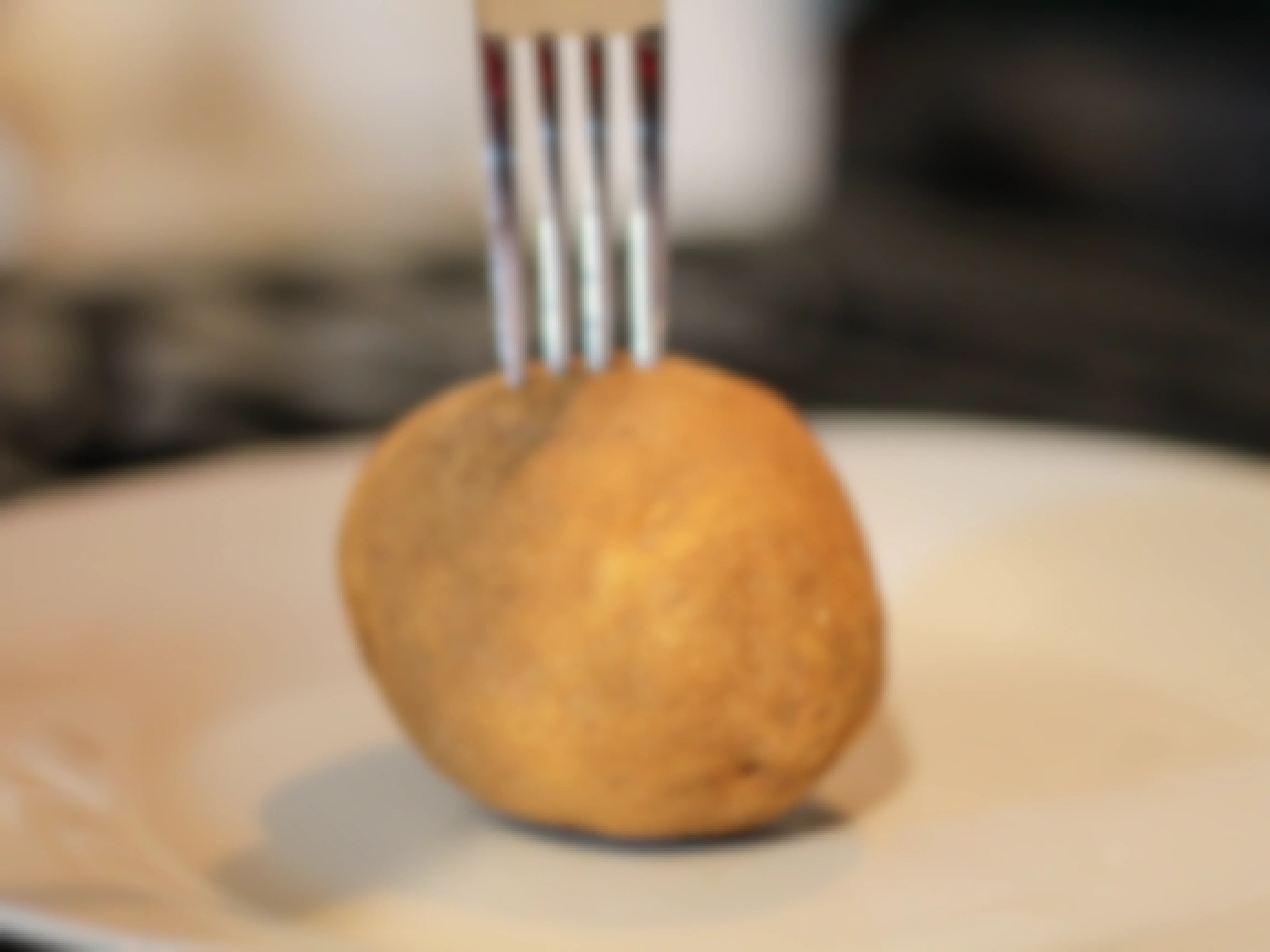 a potato with a fork going into it before the microwave