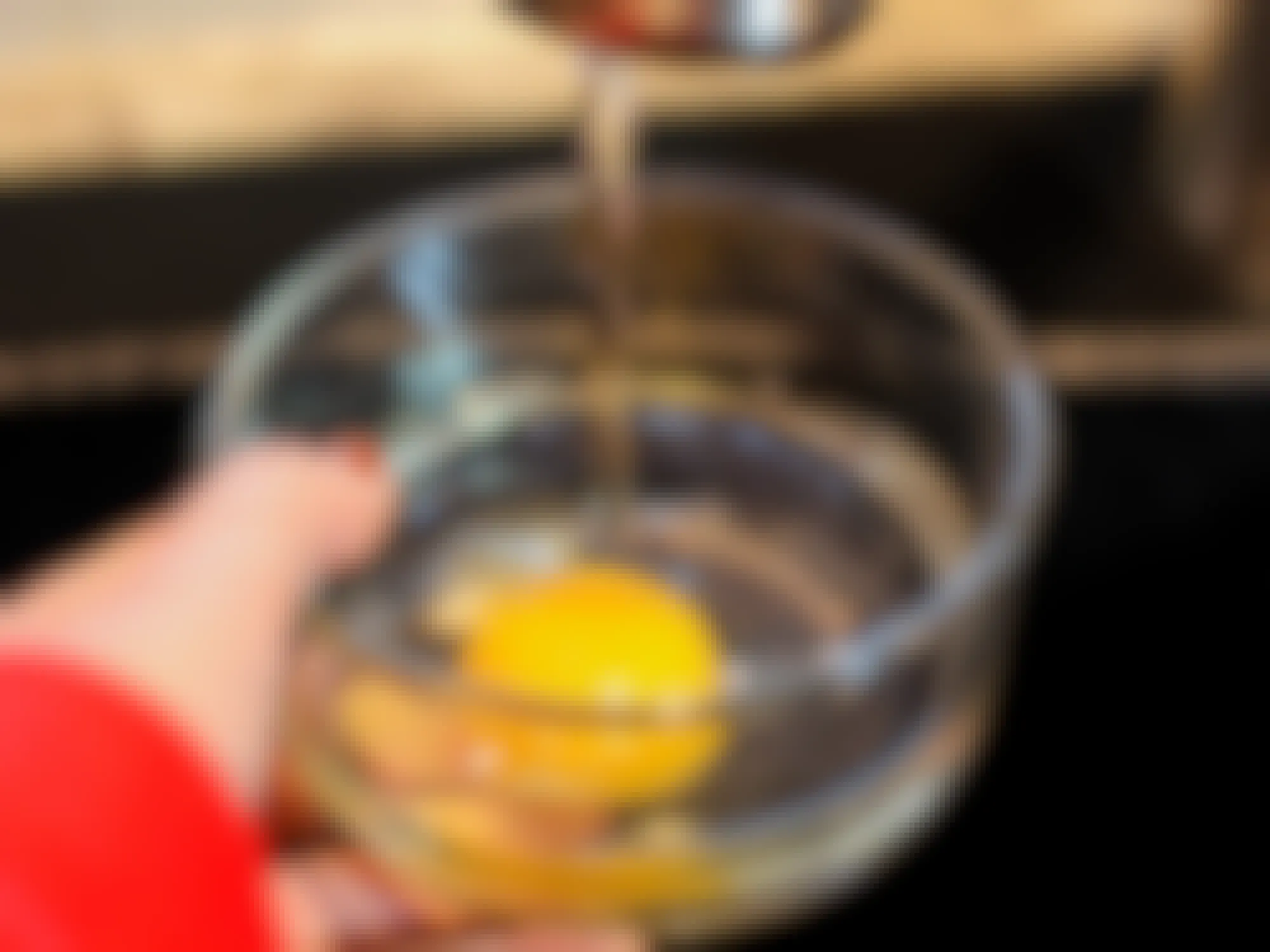 a cracked egg in a glass bowl with water from a water faucet going into the bowl