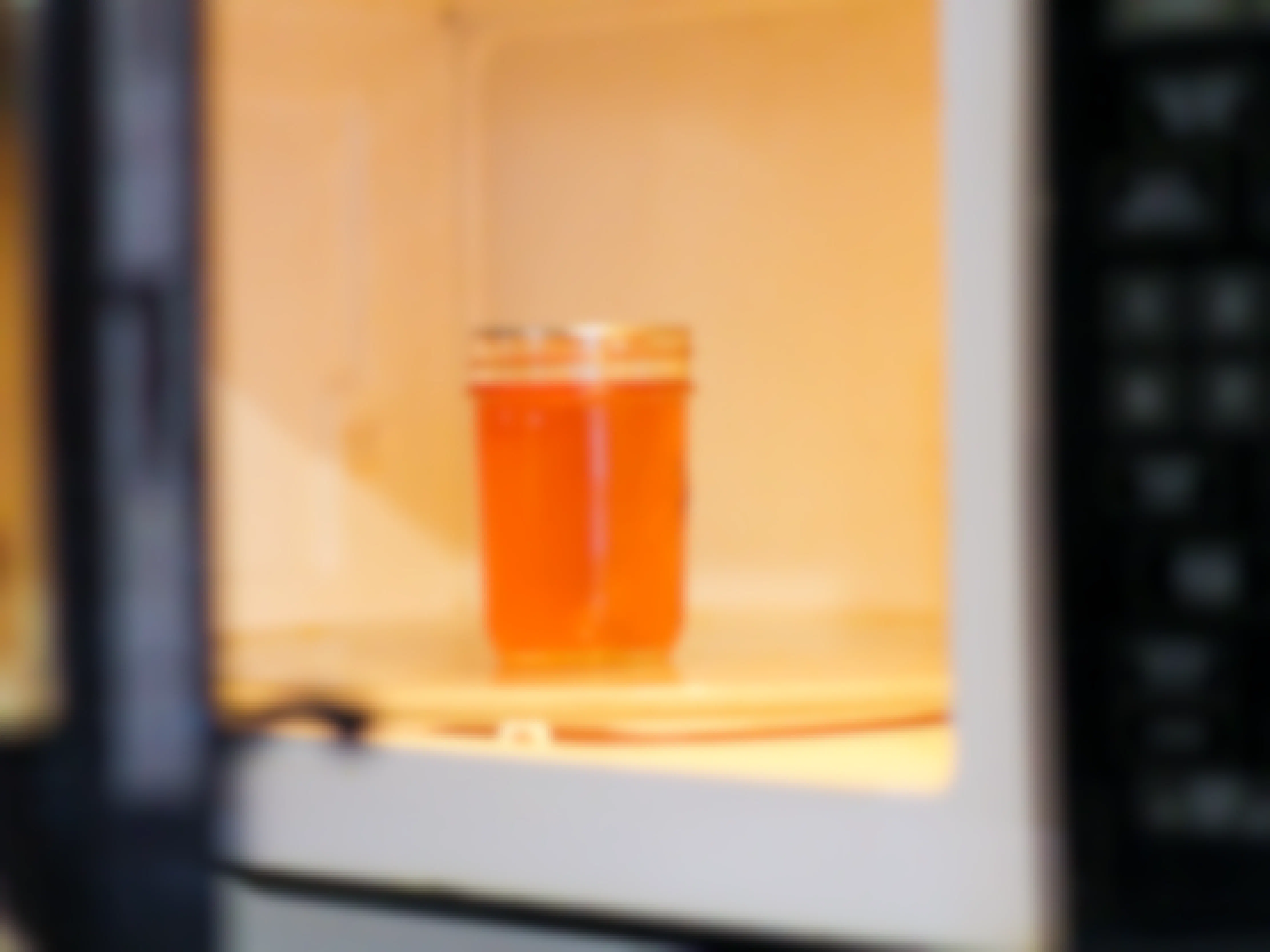 a glass jar of honey inside of a microwave