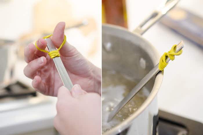 A person wrapping a rubber band around the handle of a mixing spoon, and the mixing spoon resting on the side of the bowl, not falling in due to the rubber band handle.