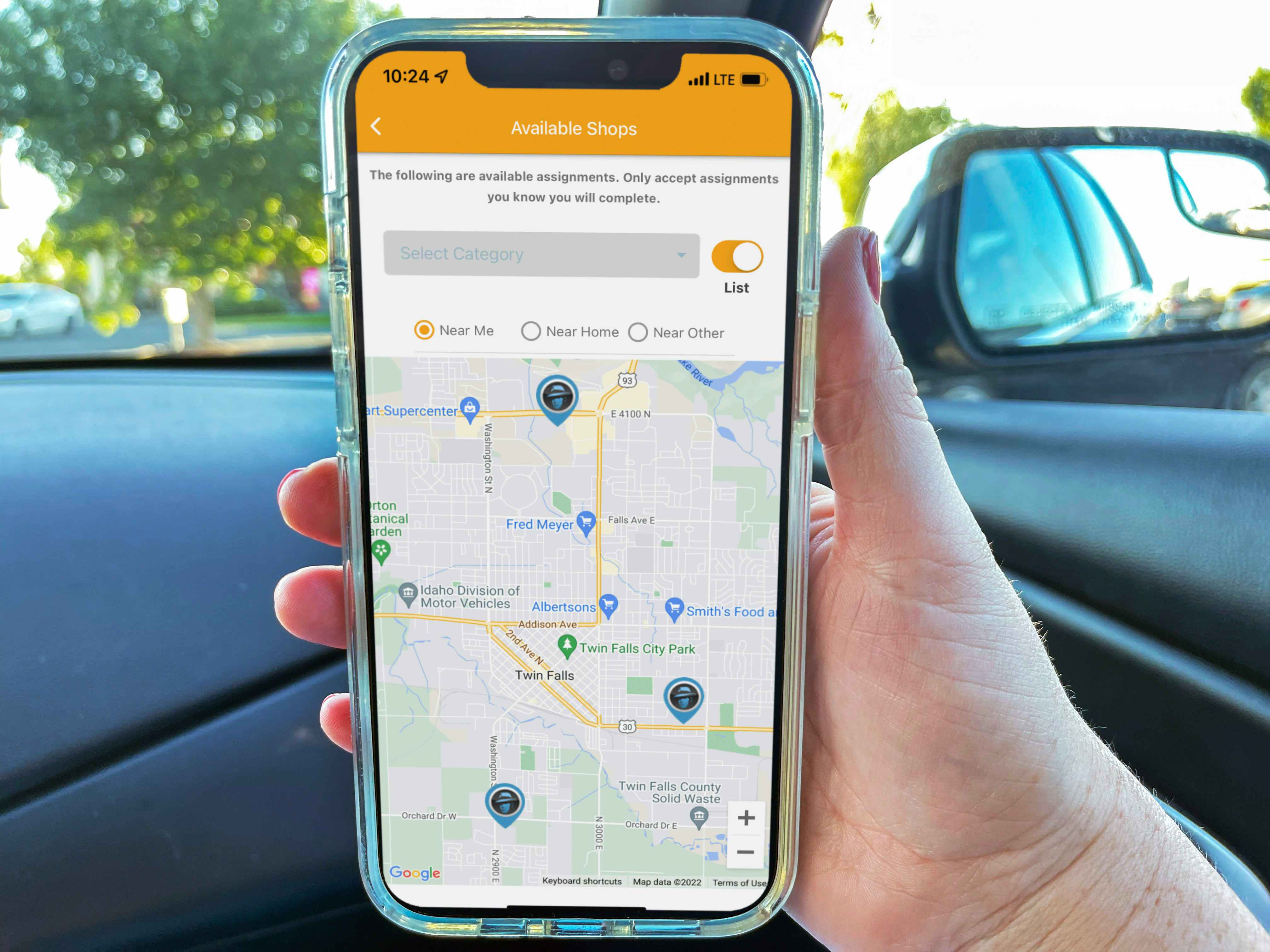 a person holding a cellphone with mystery shopper map on screen while person sitting in car
