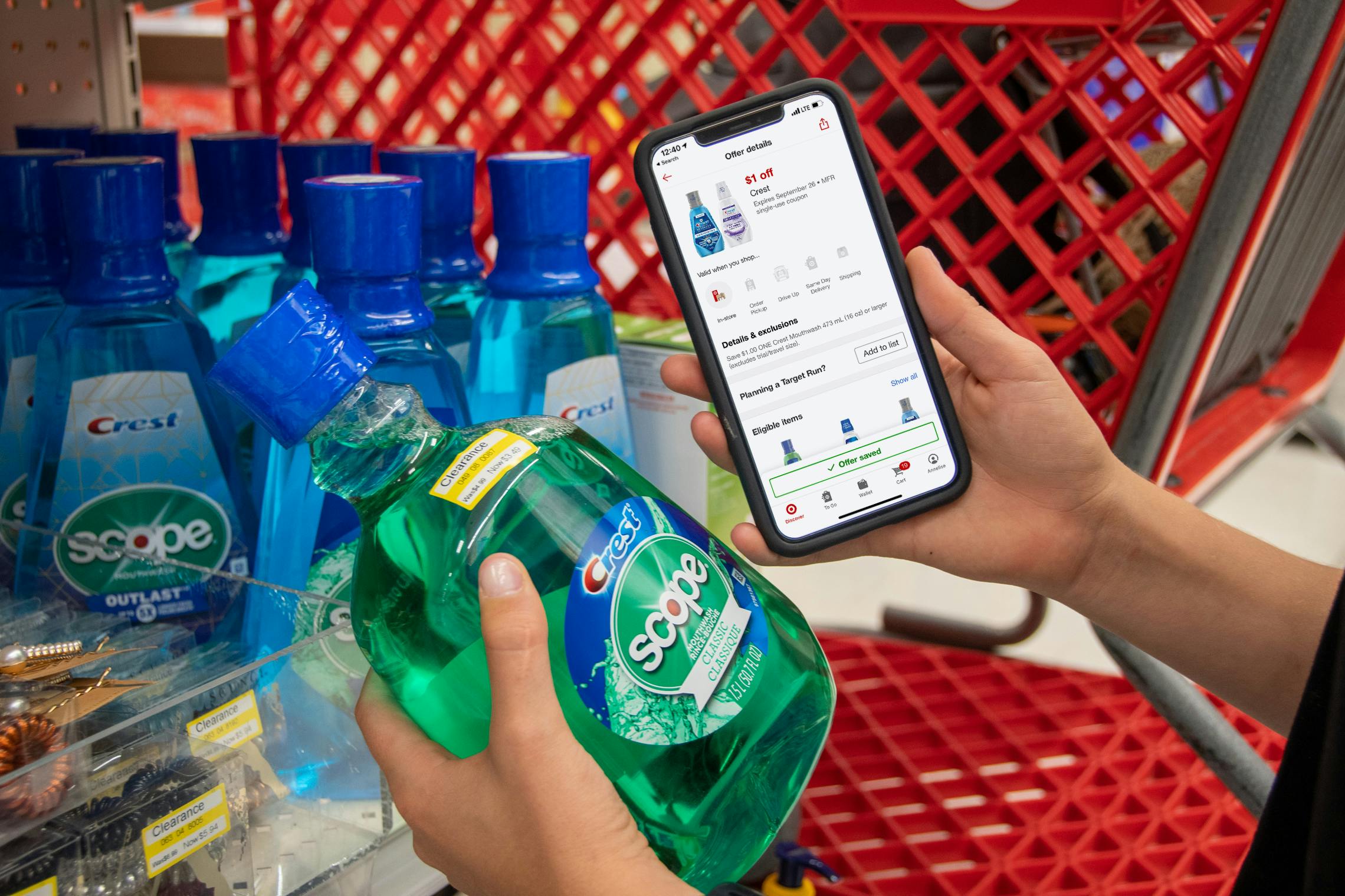 A person holding their phone displaying a Target circle app coupon next to a bottle of Scope mouthwash with a clearance sticker in Target.