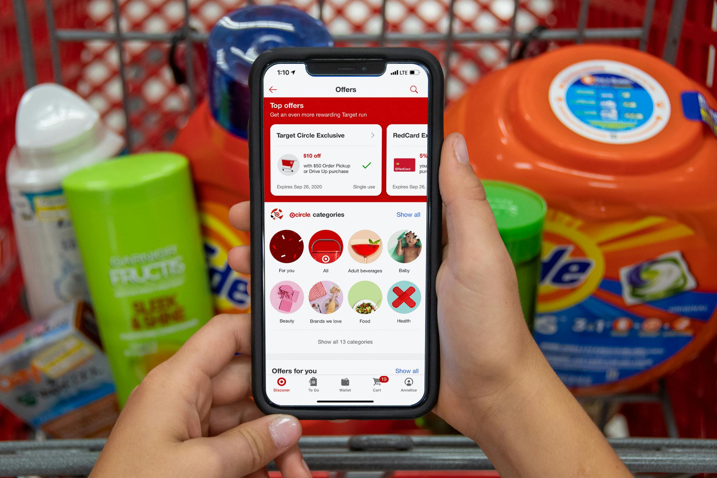 The deals page open on the Target app with a basket filled with products behind it.