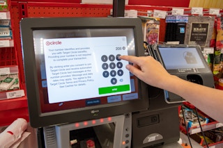 A person typing in their phone number for Target Circle at self-checkout.