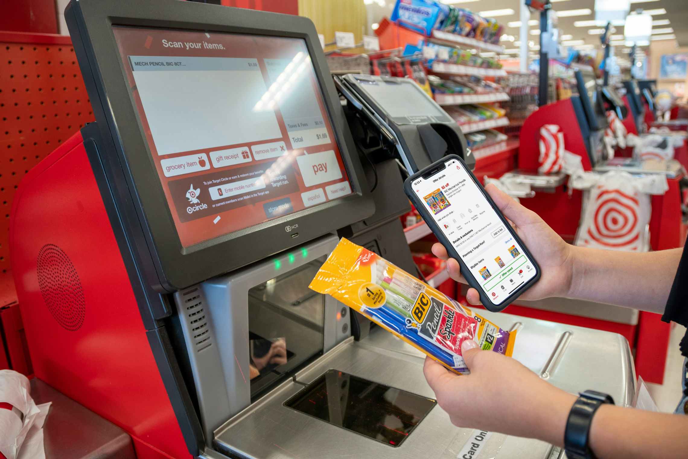 A person holding their phone next to a pack of BIC mechanical pencils at the self-checkout scanner inside Target.