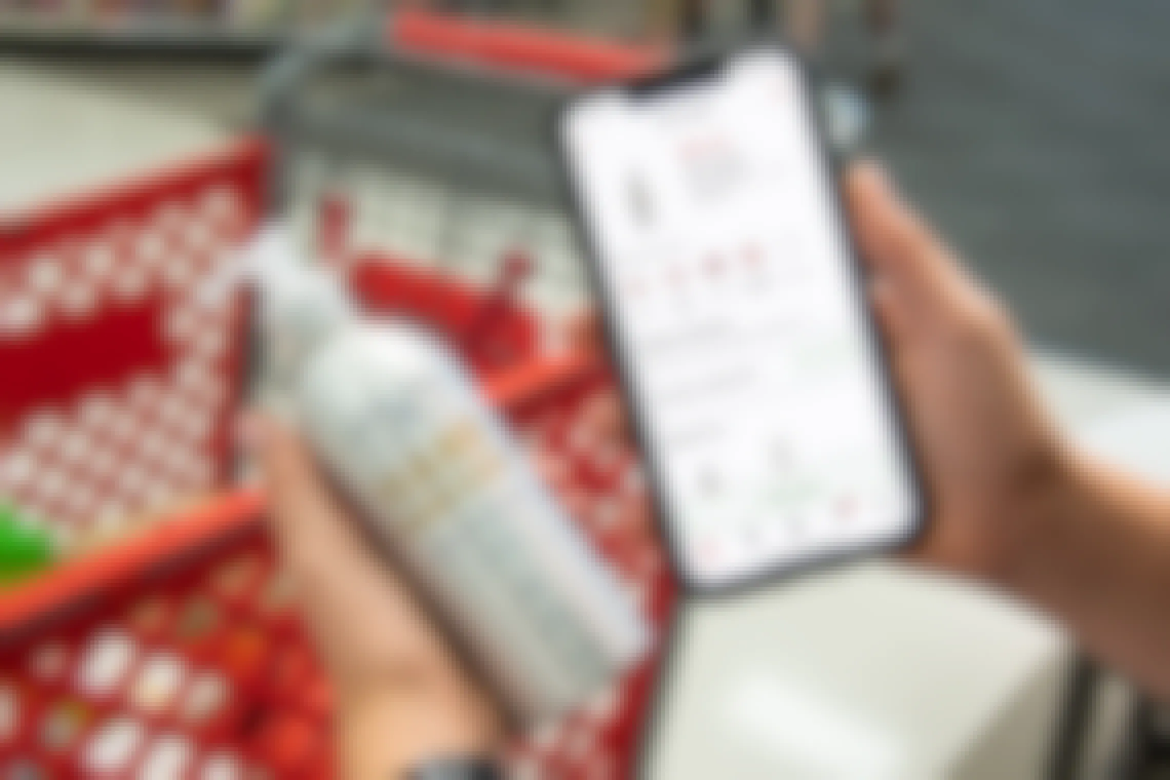 A person holding a bottle of Hand in Hand hand sanitizer next to a cell phone displaying Target app with a 30% coupon for the hand sanitizer.