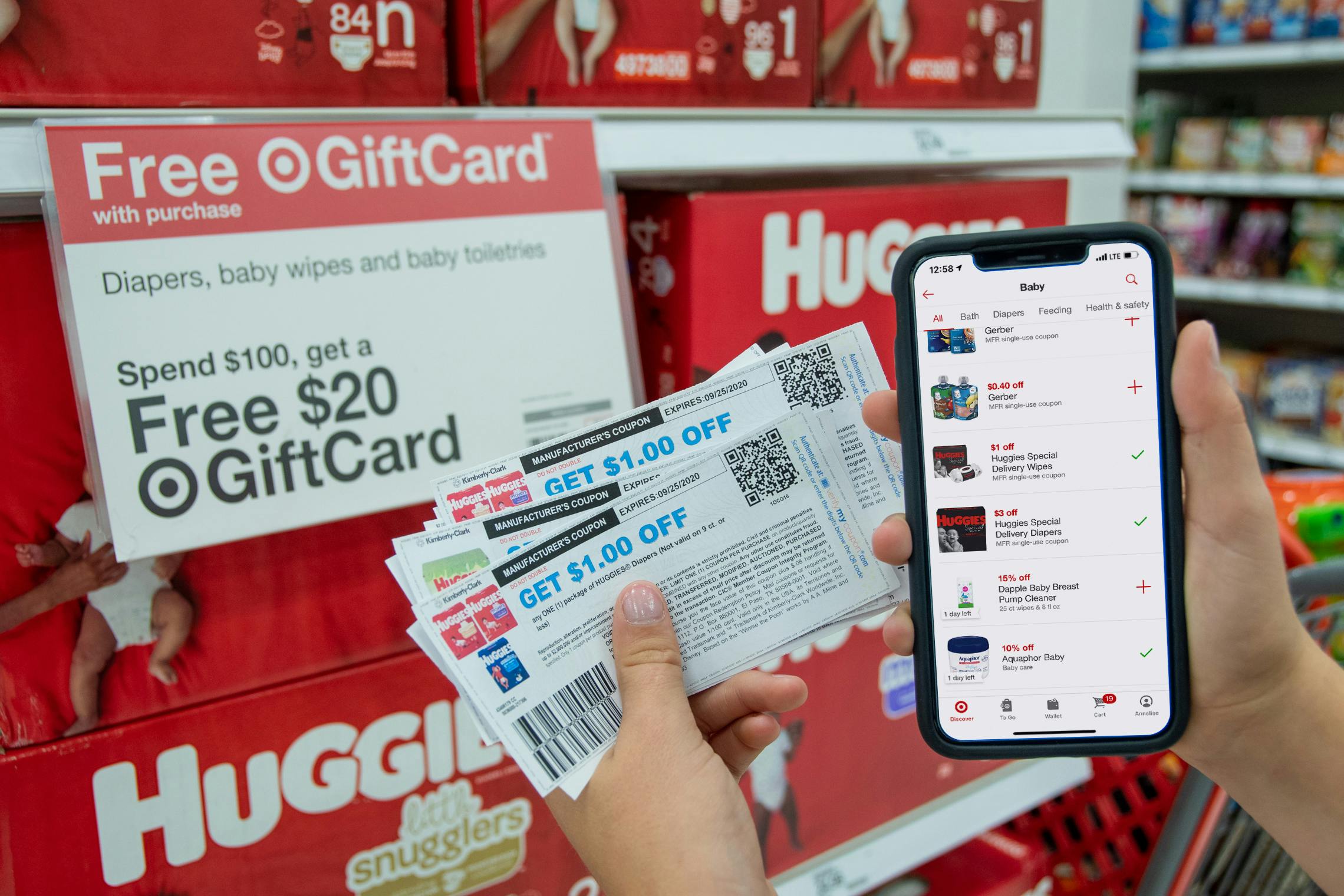 Coupons and a cell phone next to huggies diapers and a Free Gift Card Sign