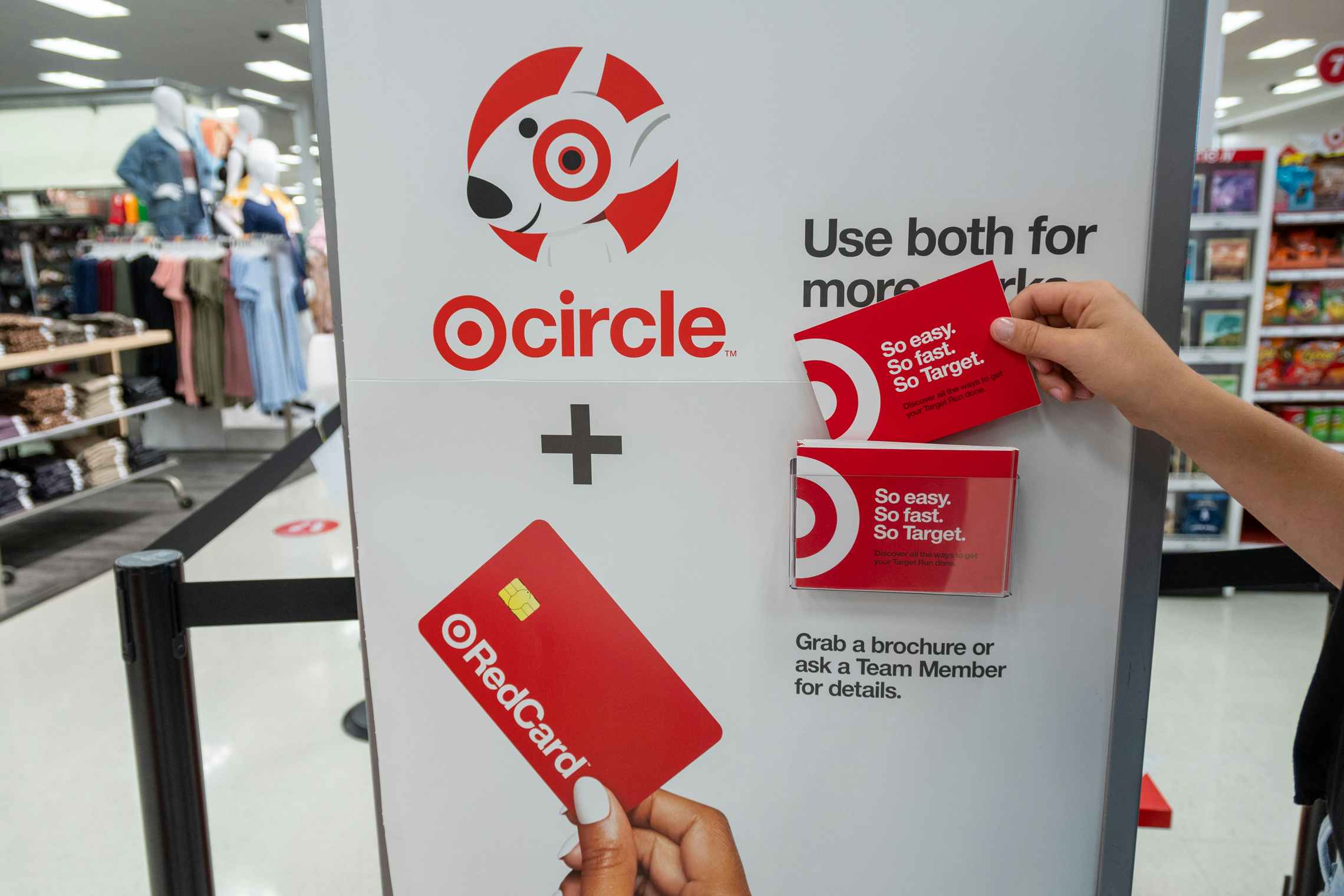 A person taking a brochure from the Target Circle and RedCard information stand inside Target.
