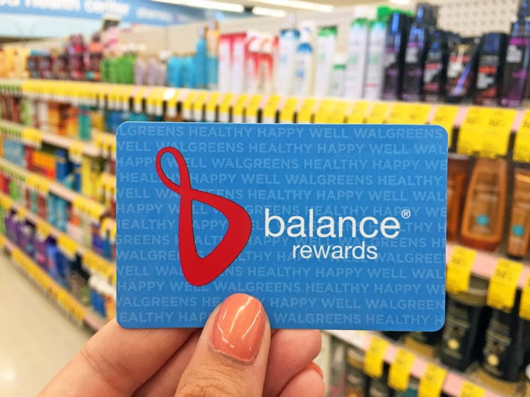 hand holds walgreens balance rewards card in front of shampoo aisle in walgreens