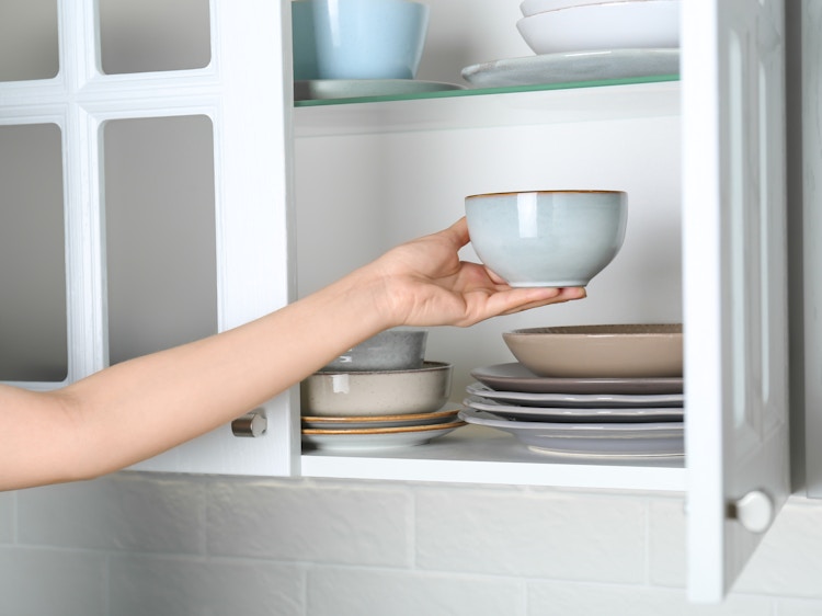 Someone organizing the dishes in their kitchen cabinet