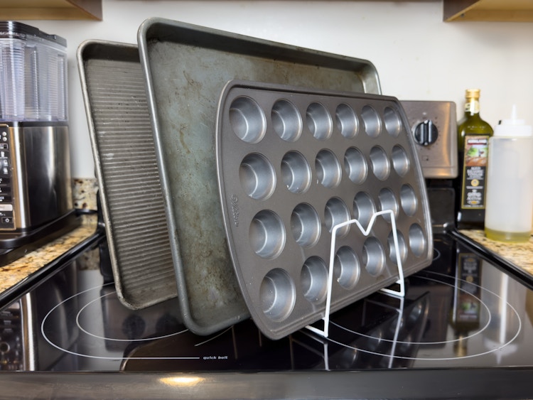 Some baking sheet pans and muffin tin organized with a small rack