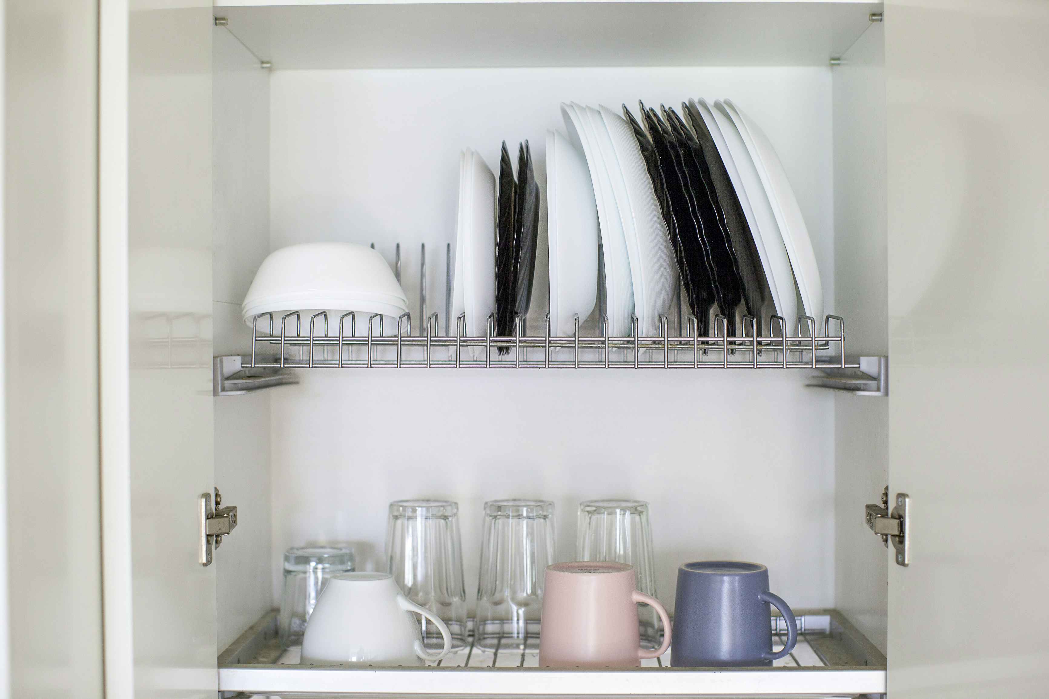 A dish drying rack inside a kitchen cabinet