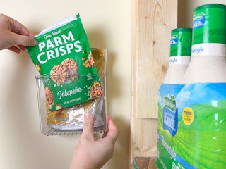 Someone putting snacks in a sink caddy on the wall of a pantry