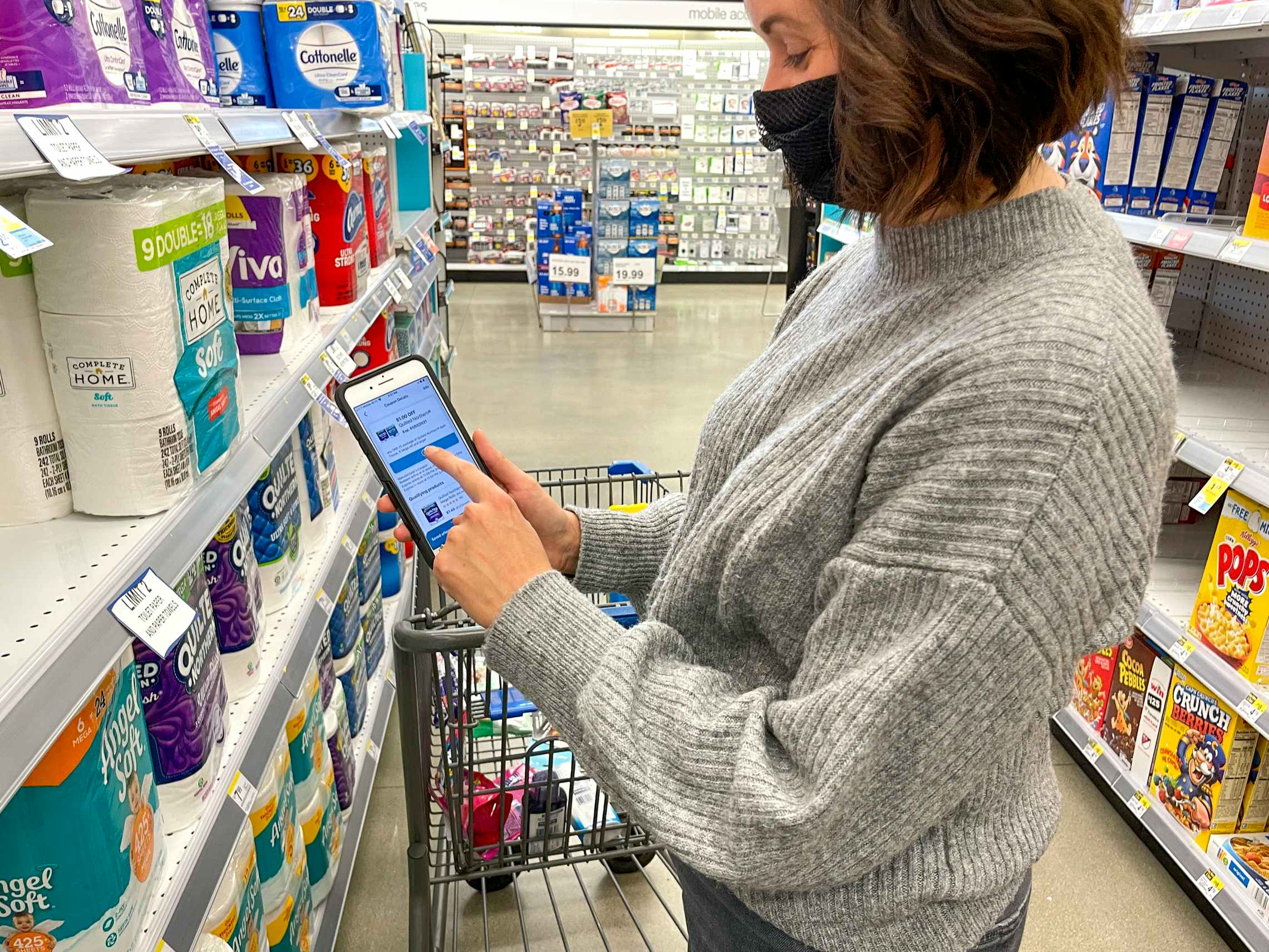 woman pointing at coupon on cell phone in walgreens