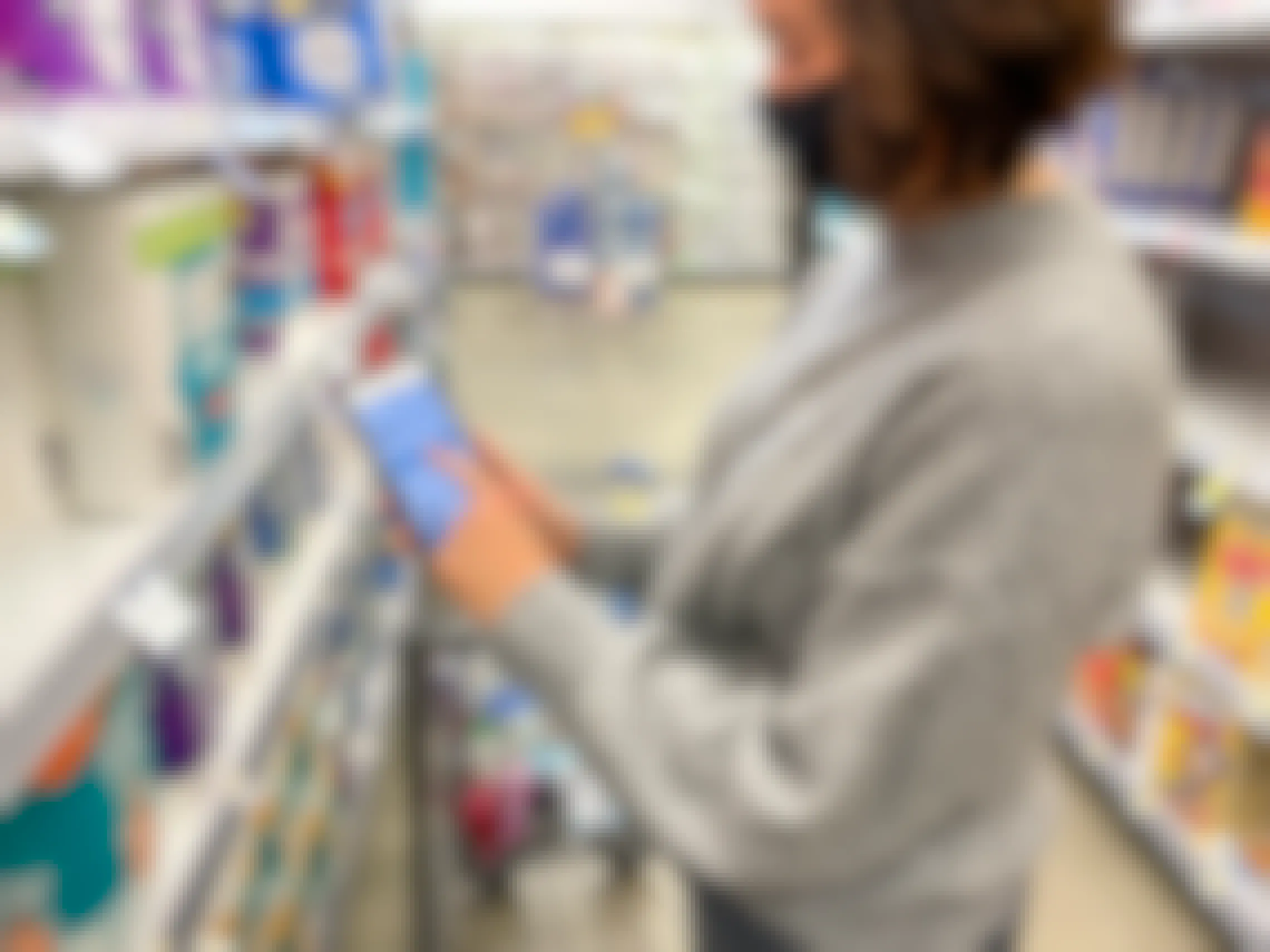 A woman pointing at coupon on her cell phone in an aisle at Walgreens.