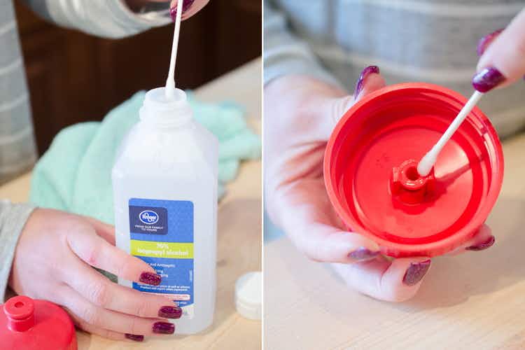 A cotton swab being dipped into a rubbing alcohol and used to clean a water bottle lid.