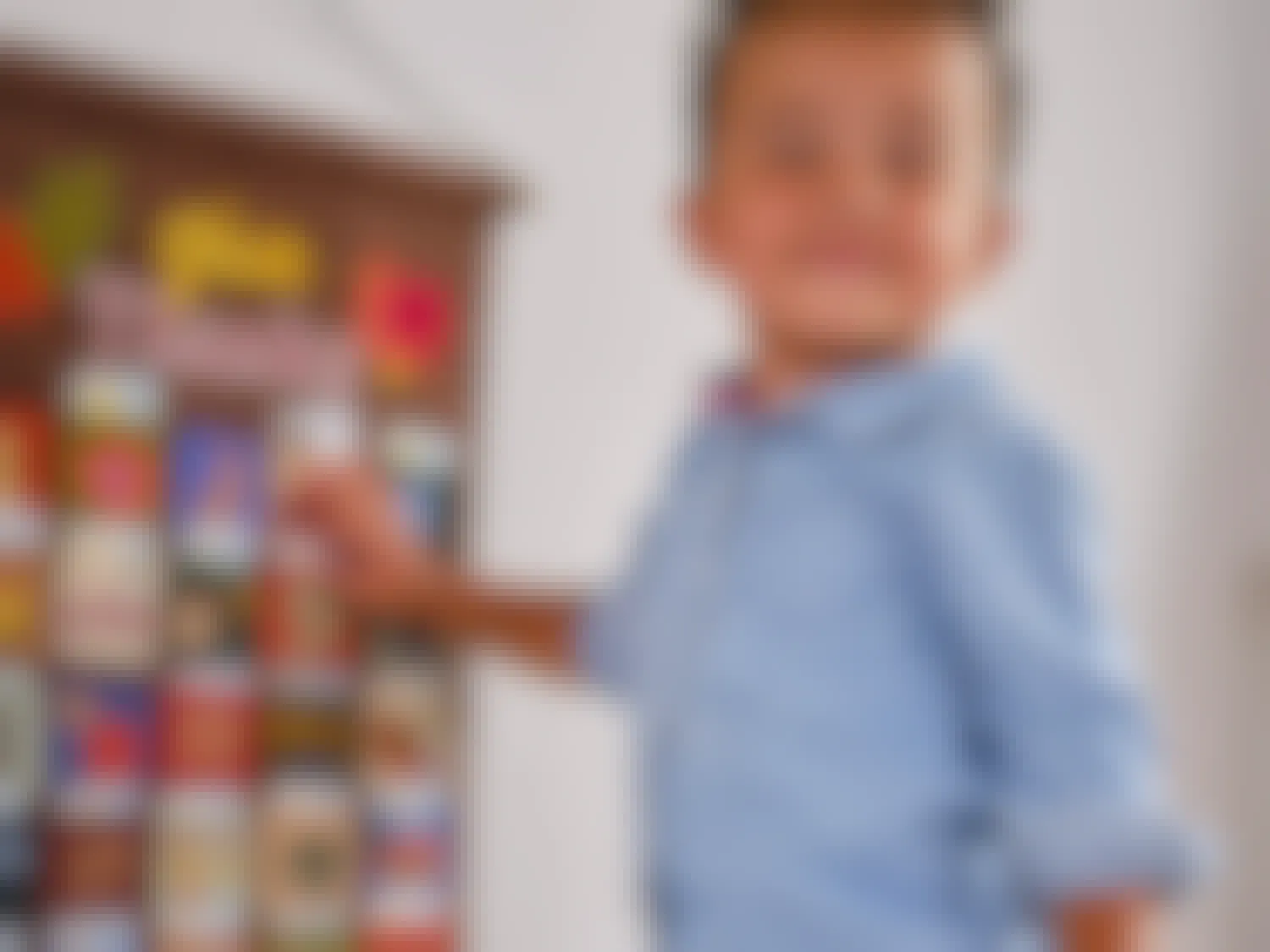 A little boy standing next to a Thanksgiving advent calendar hanging on the wall.