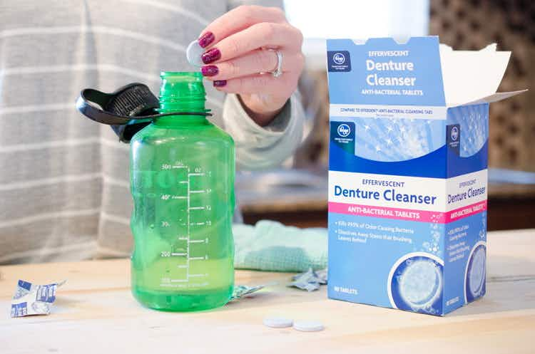 Drop a couple of denture cleaning tablets into a bottle filled with warm water to clean it.