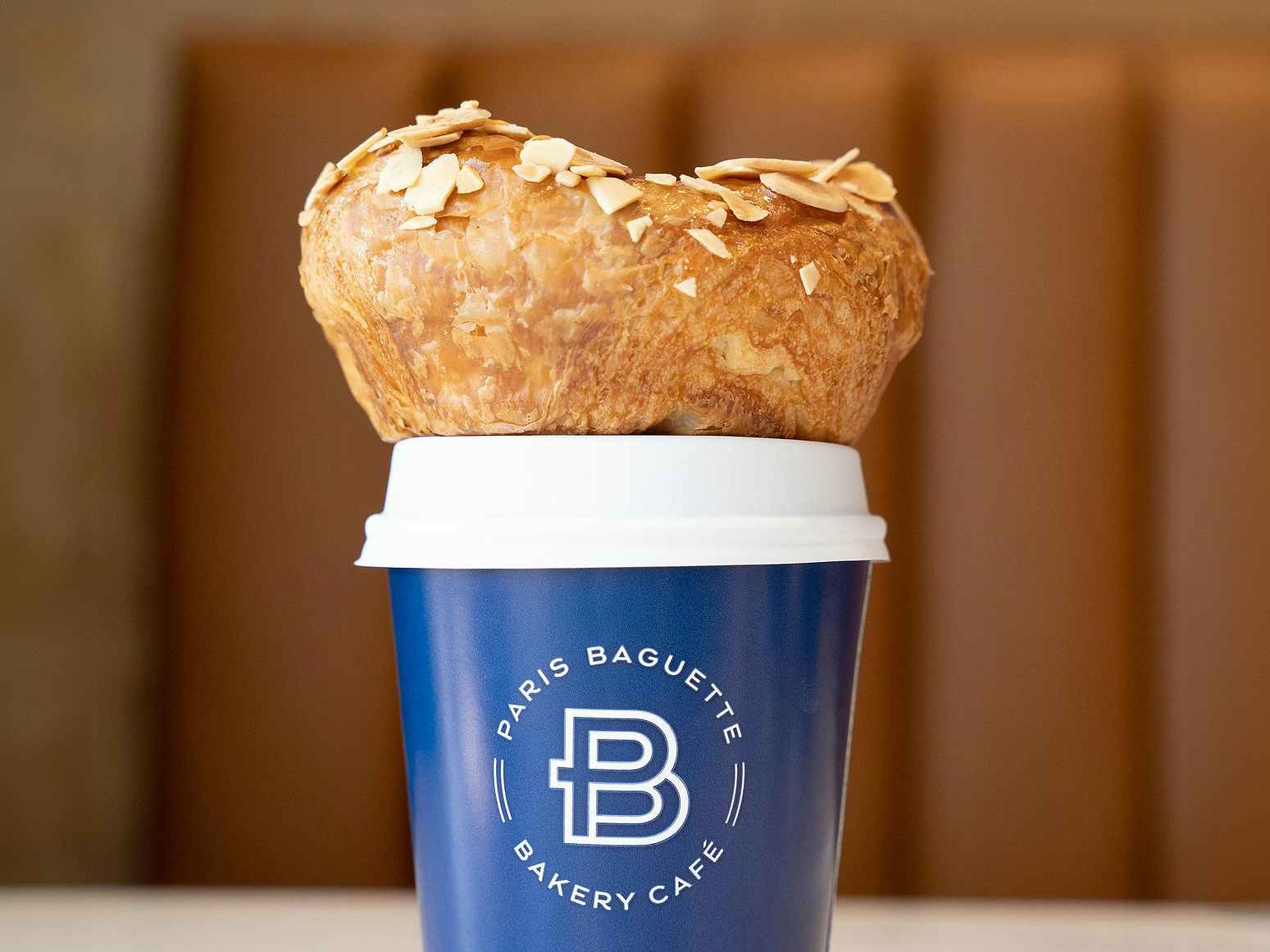 paris baguette pastry on top of to-go coffee in restaurant