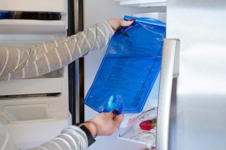 A blue Camelbak water bladder being placed in a freezer