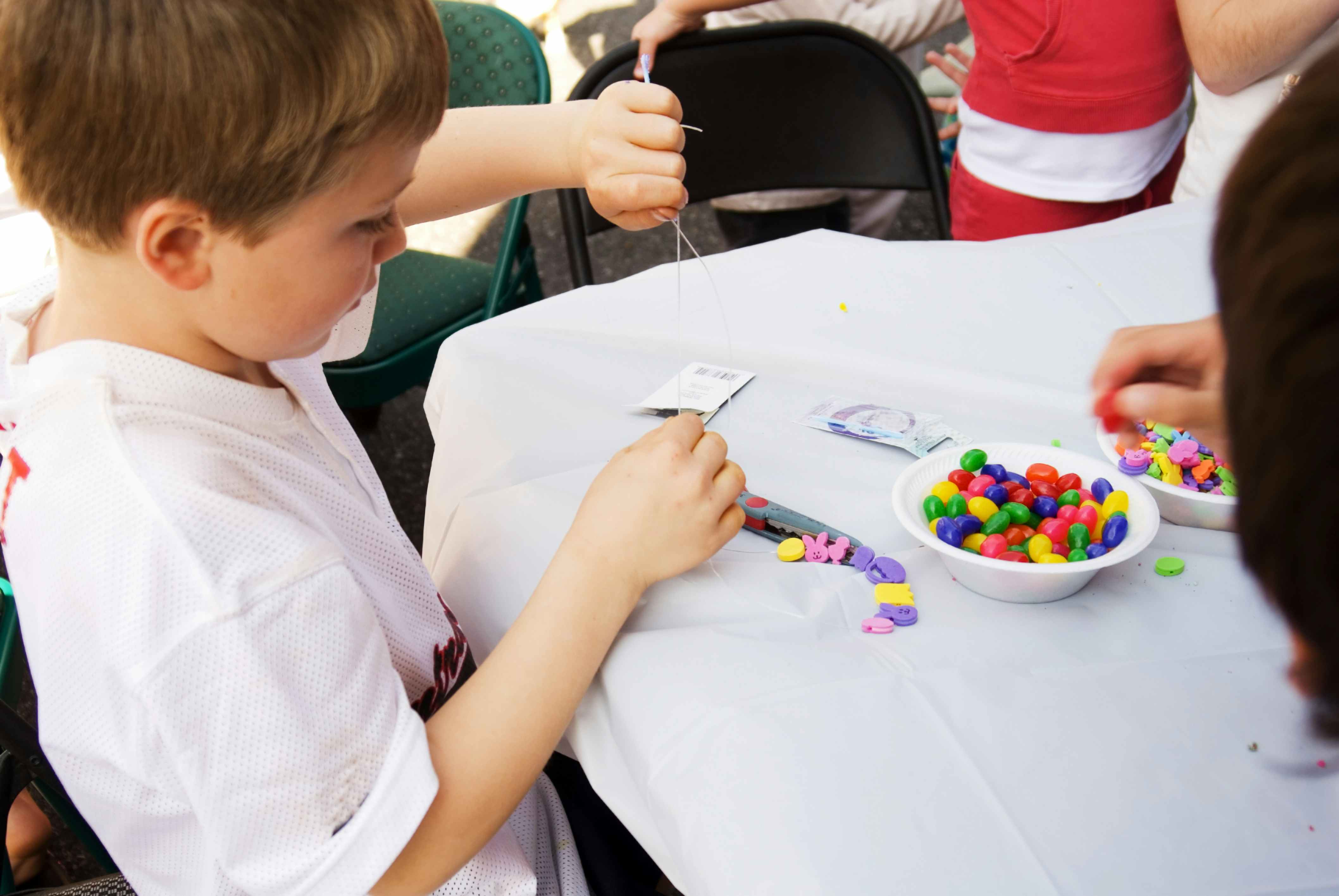 A child making a candy necklace with leftover Halloween candy.