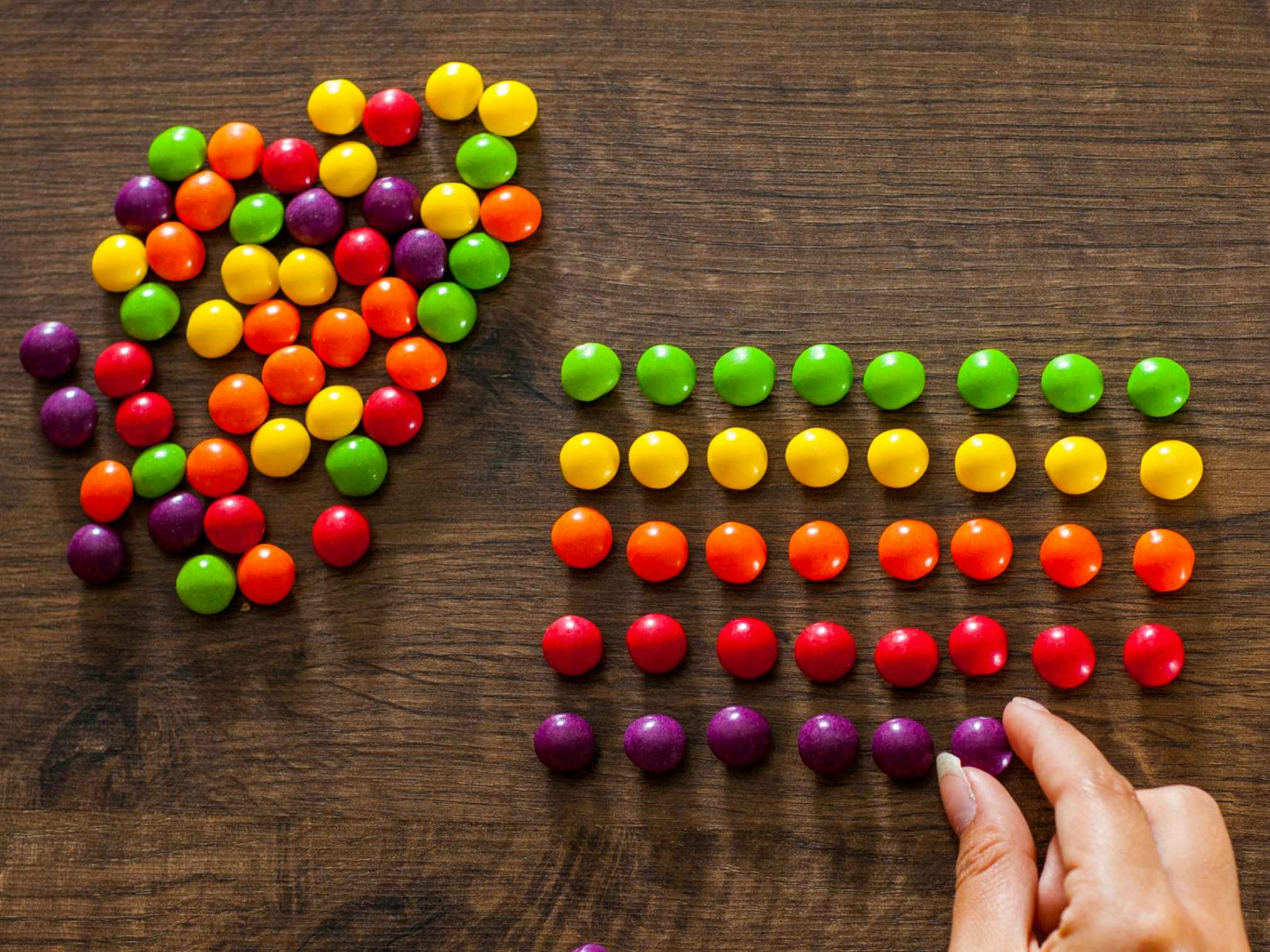 A person sorting skittles by color