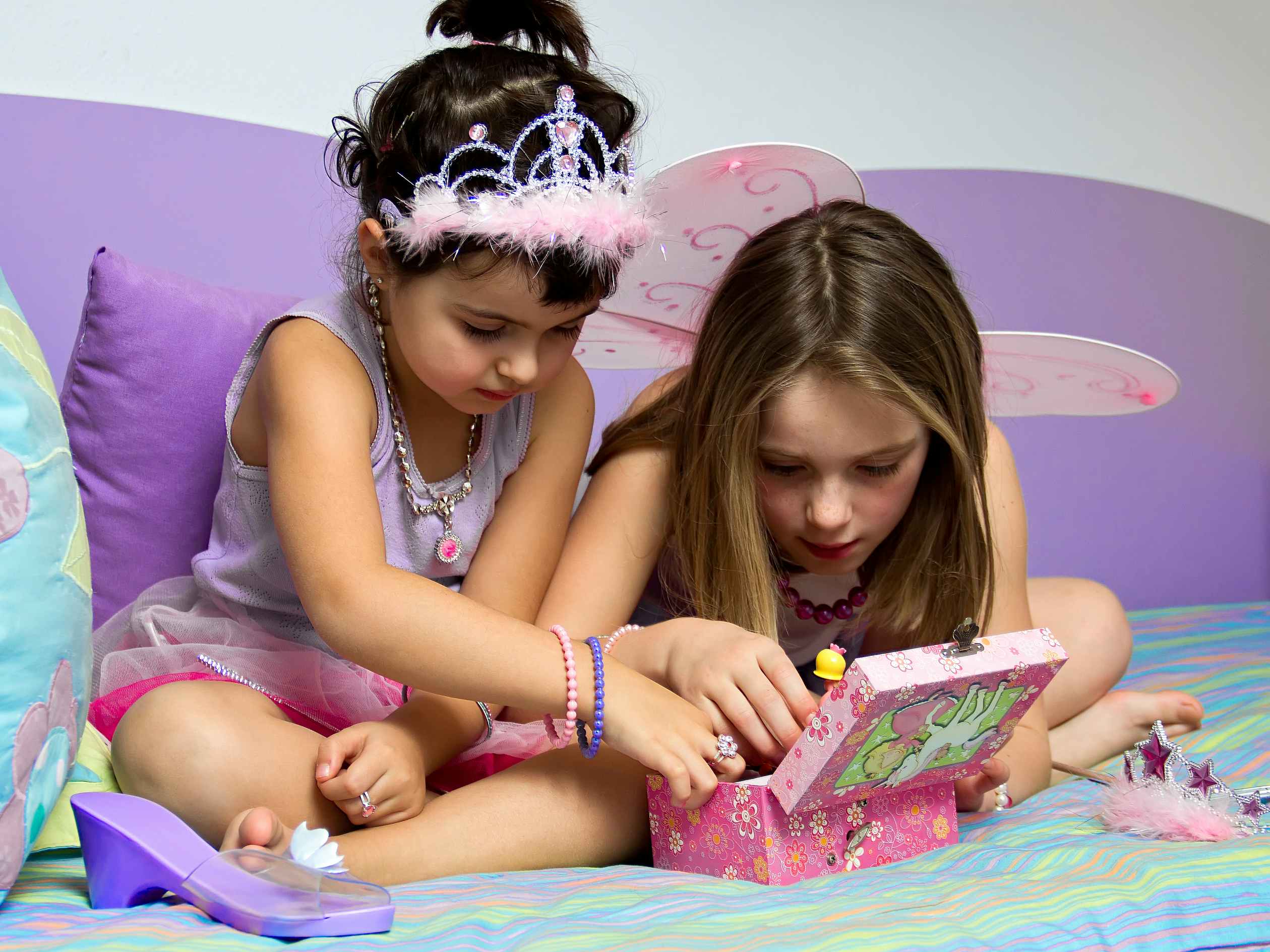 Two kids playing dress up with fairy princess costume pieces.
