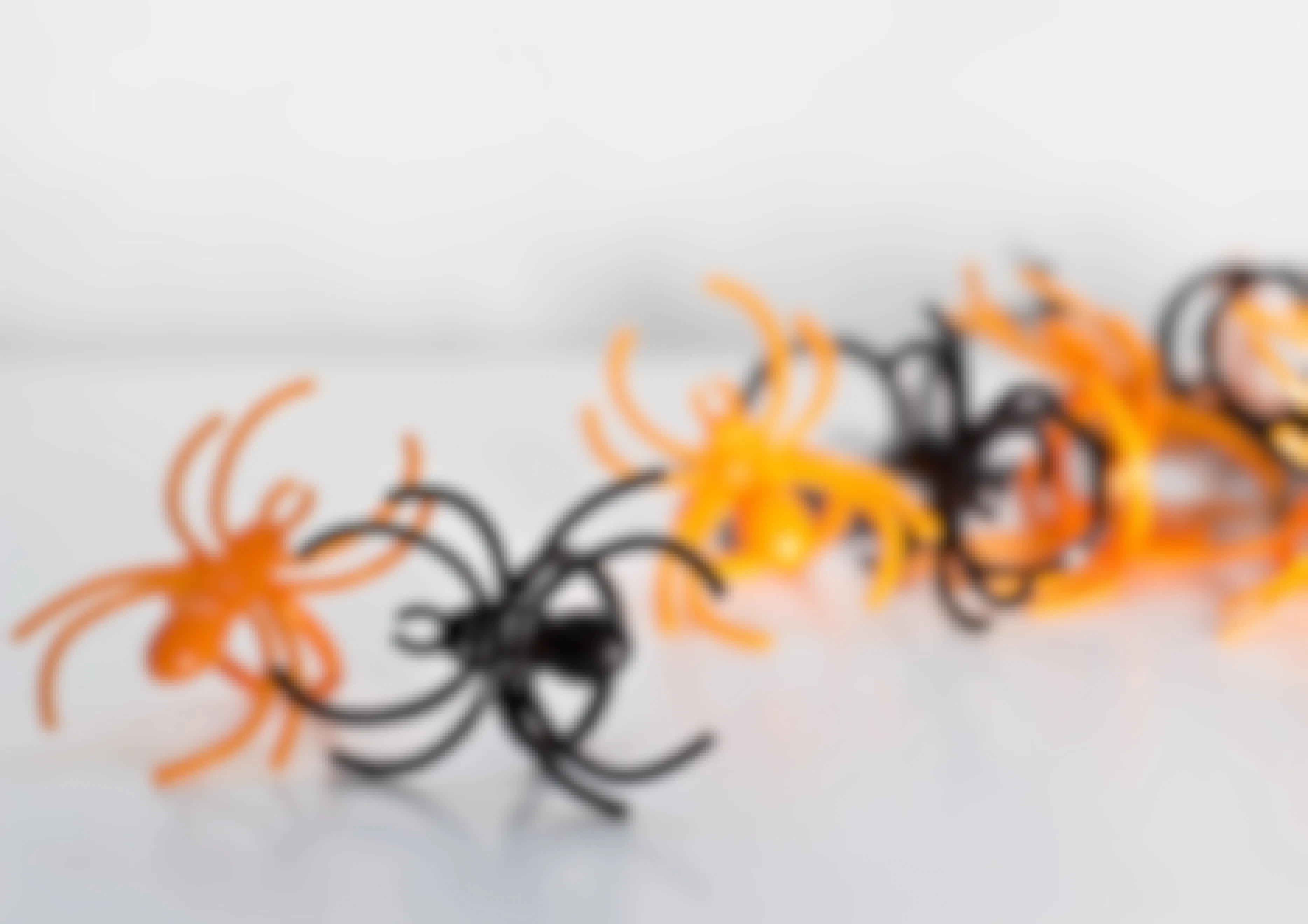 Some orange and black plastic Halloween spider rings on a table.