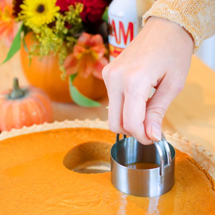 woman pressing biscuit cutter into pumpkin pie