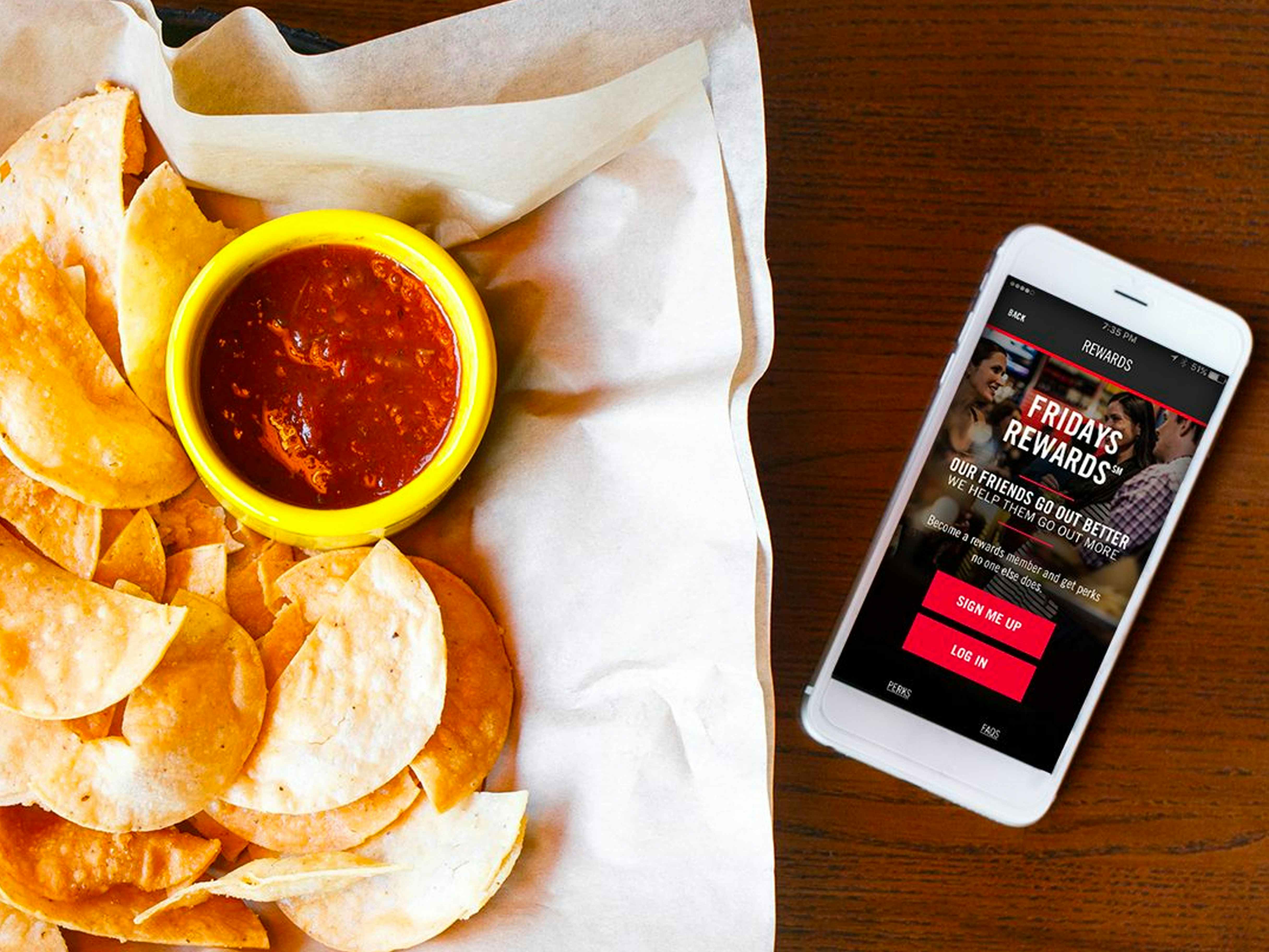 Plate of chips and salsa with a cell phone on a wooden table
