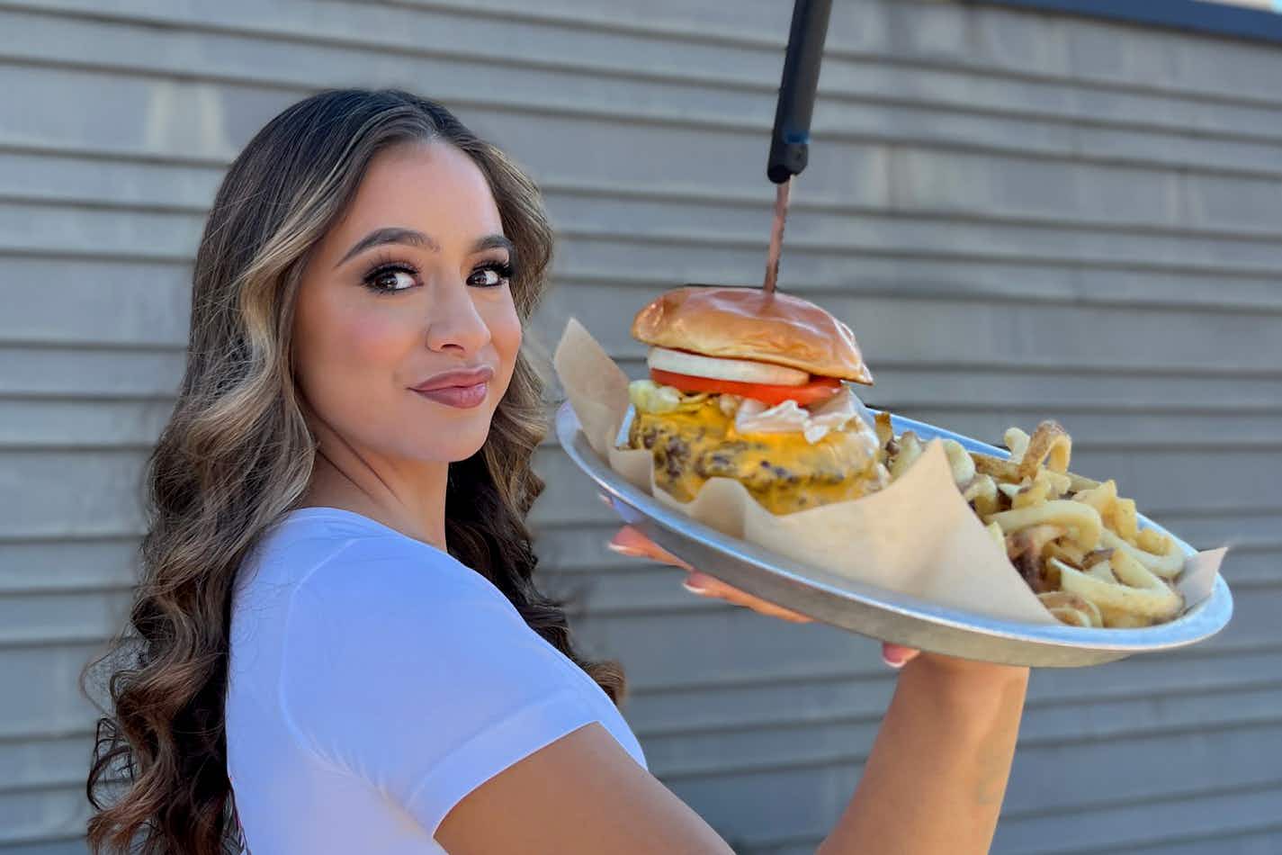 hooters server holding a burger and fries on a tray