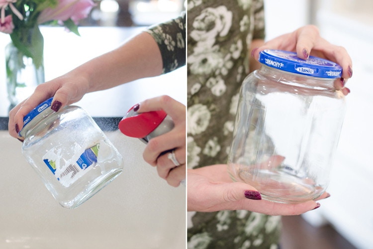 Person spraying a solution onto a pickle jar with the label half removed 