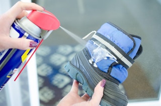 Someone spraying WD-40 onto a child's snow boot