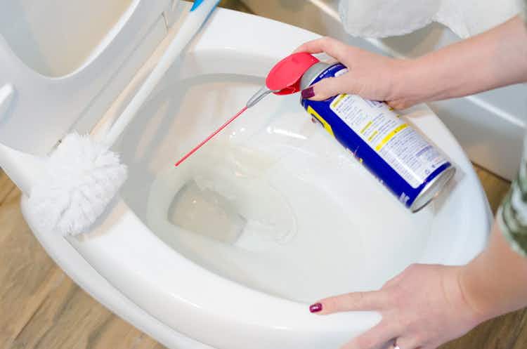 woman cleaning a toilet with this WD-40 toilet hack.