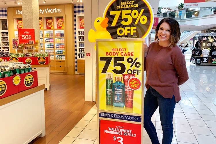 woman standing next to bath and body works clearance sign