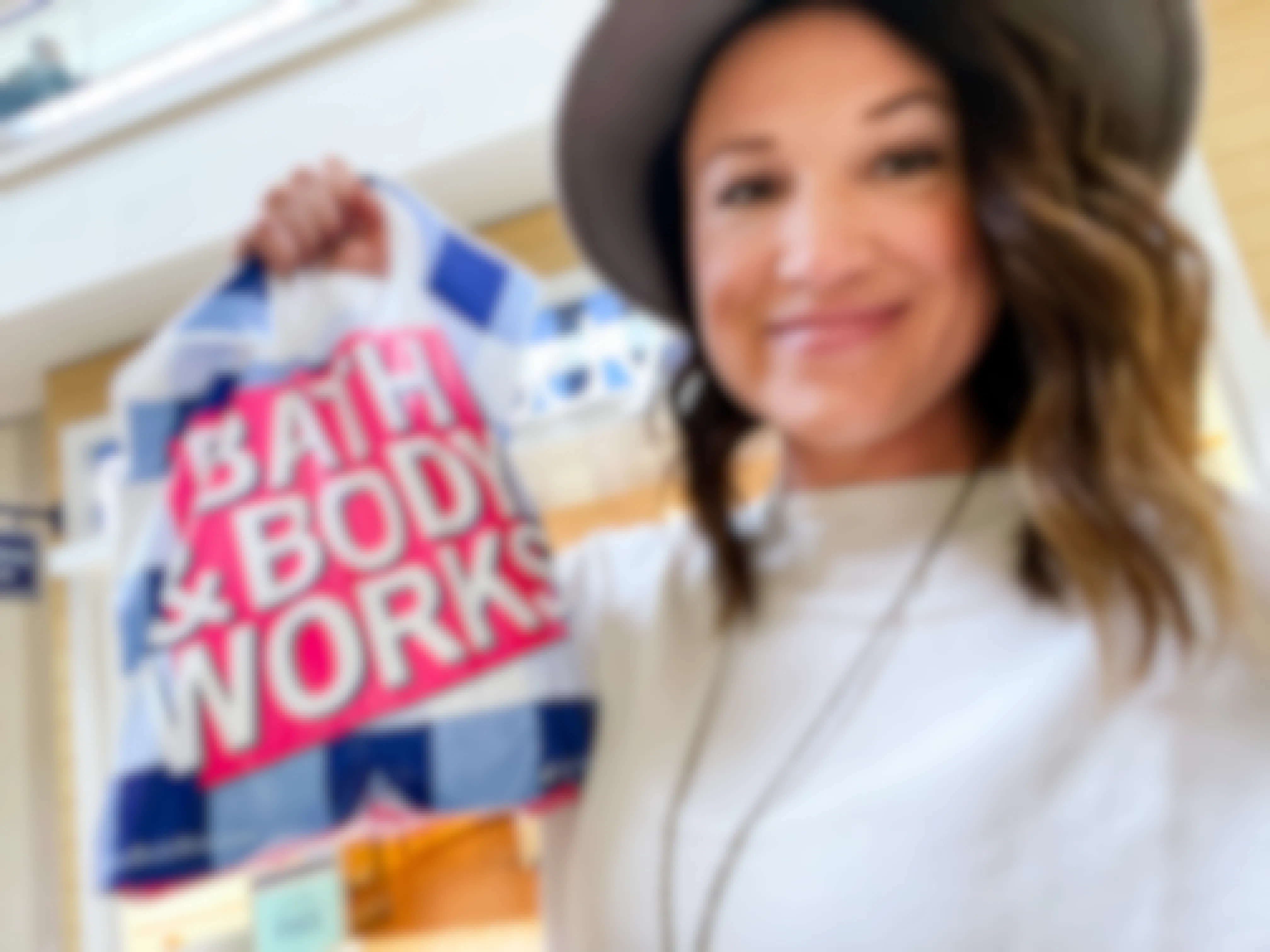 a woman holding up a bath and body works bag.