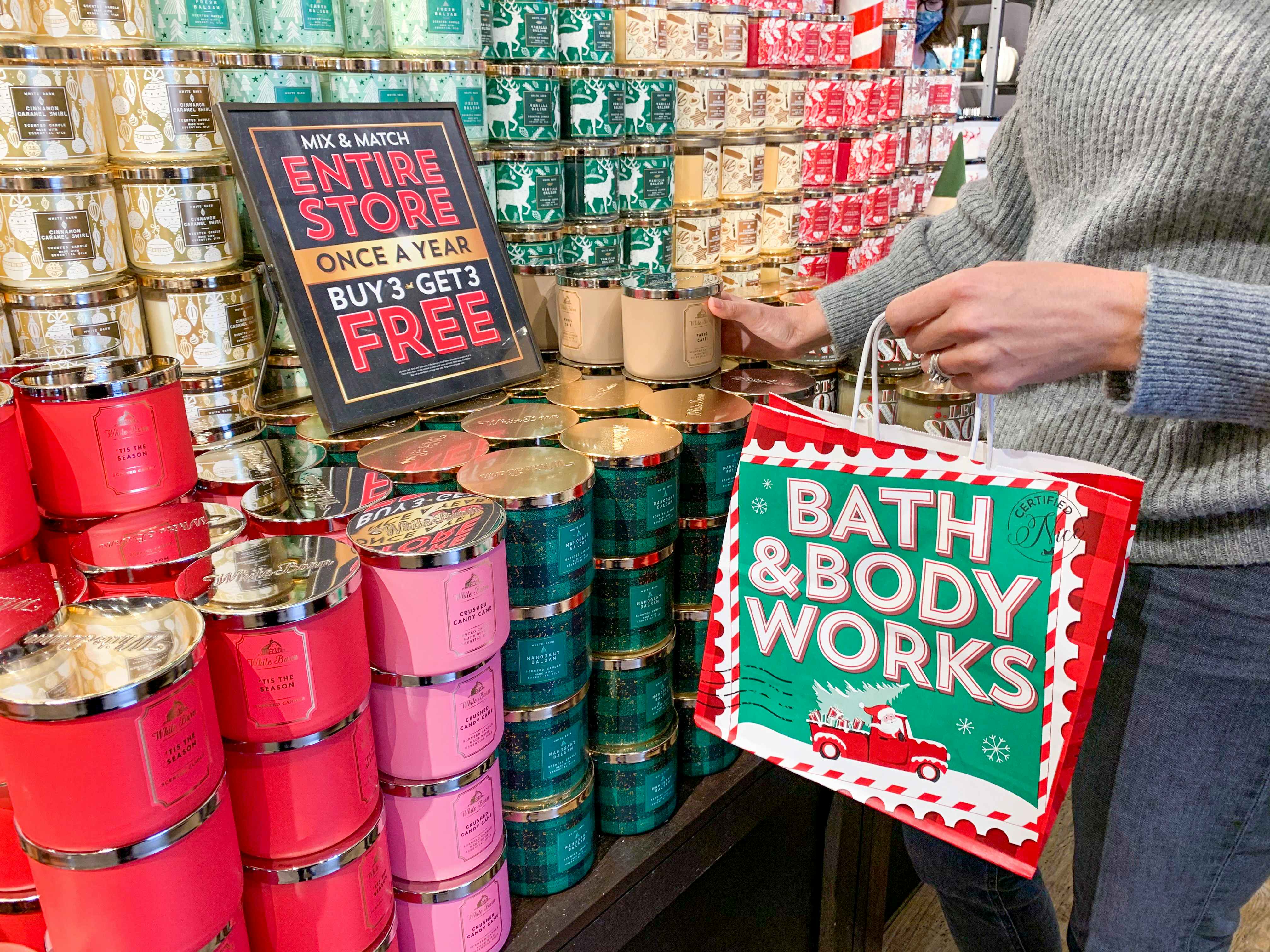 A woman holding a Bath & Body works bag, shopping for candles at the Bath & Body Works Black Friday sale