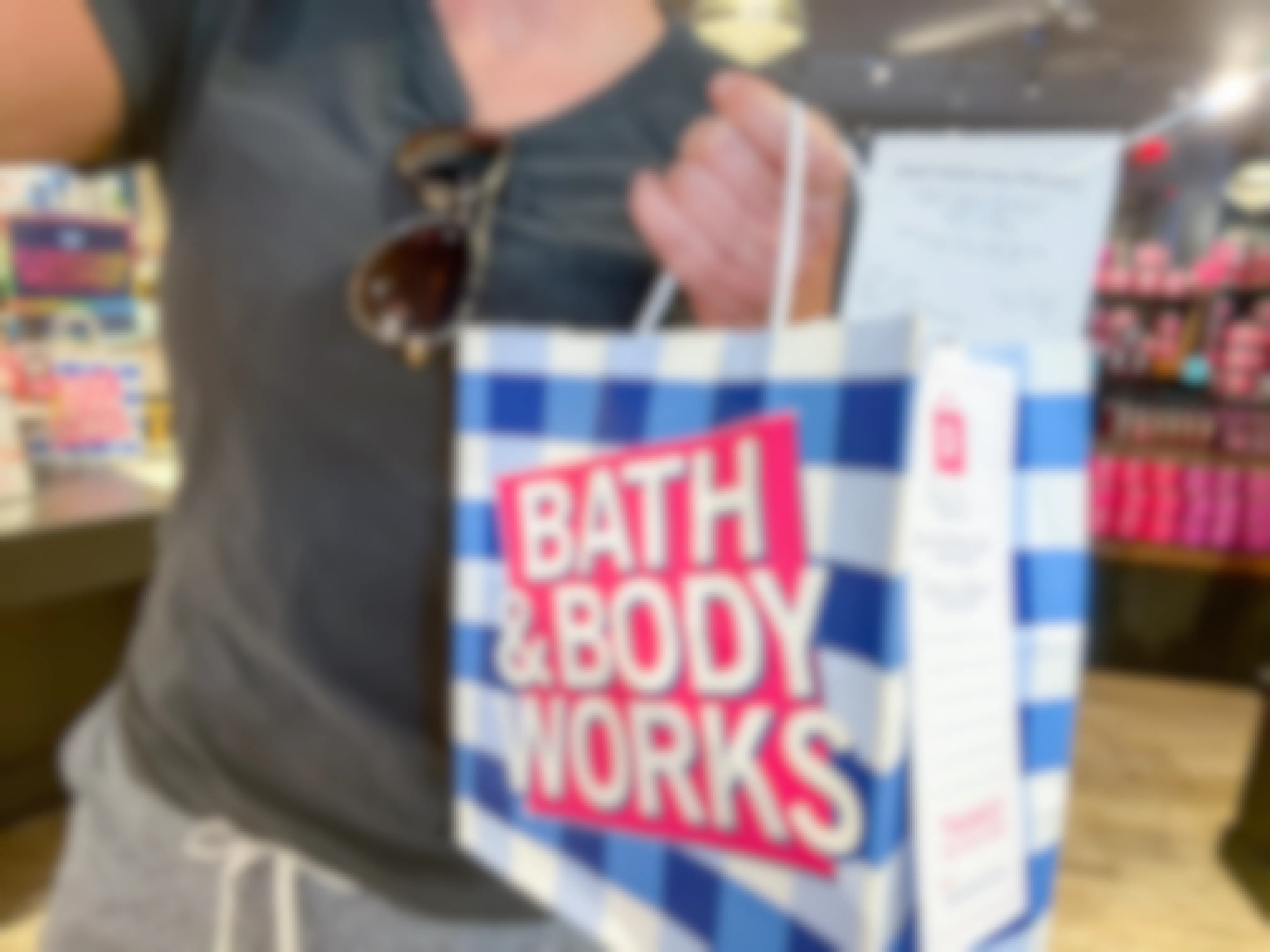 A woman standing in Bath & Body Works, holding her online order that she picked up in-store.