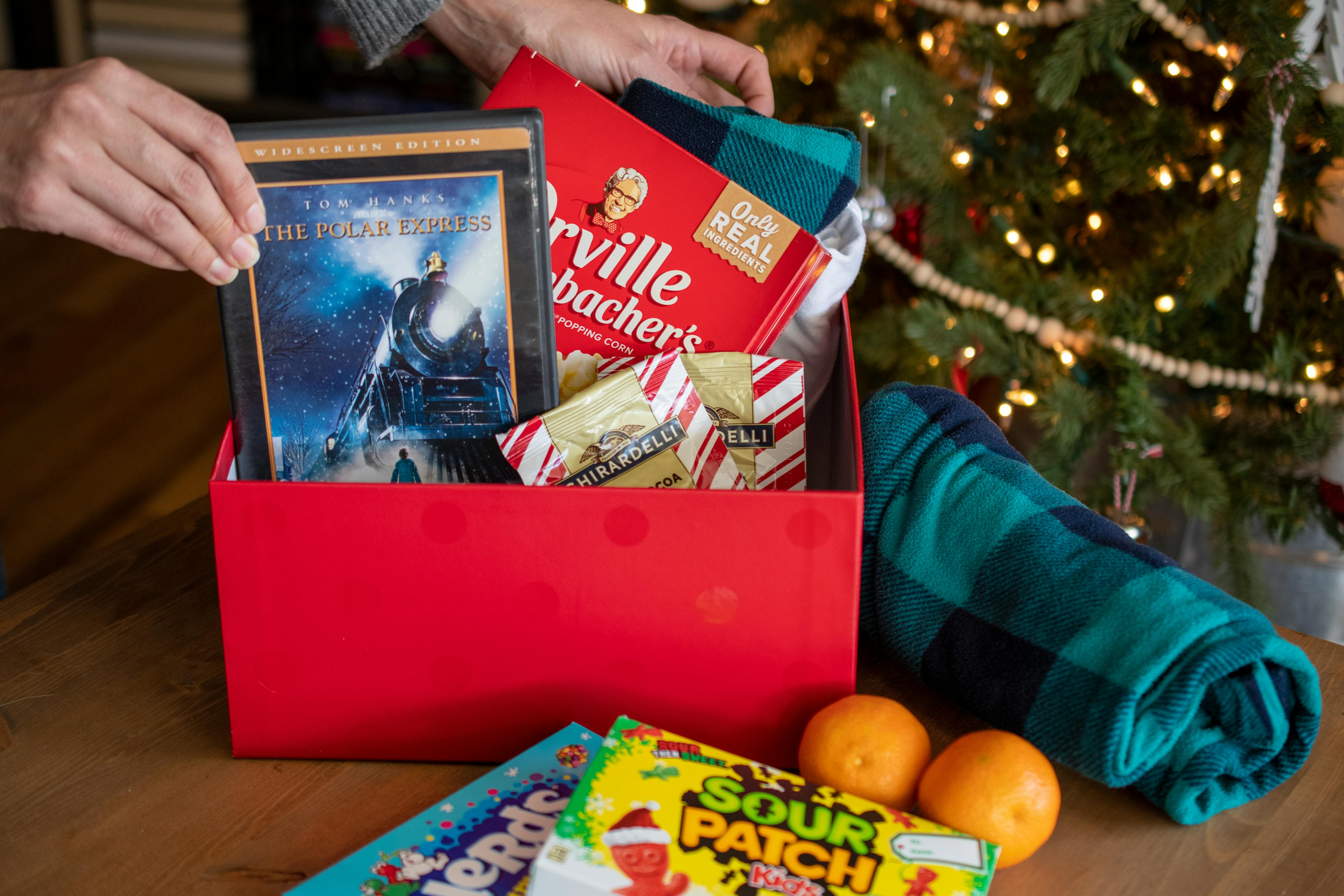 A red box filled with PJs, popcorn, candy, hot chocolate, and a movie.