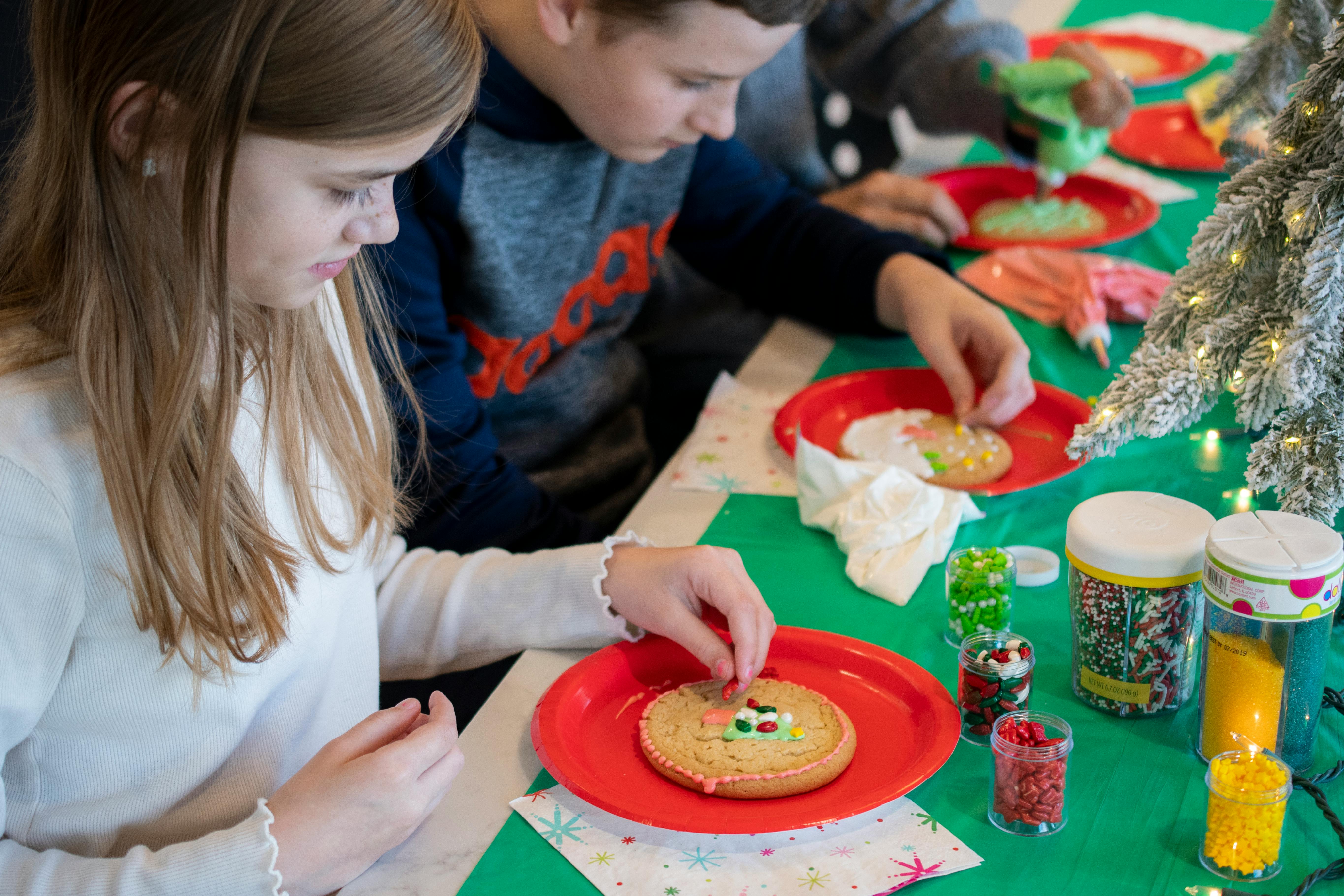 Some kids decorating Christmas Cookies at a table
