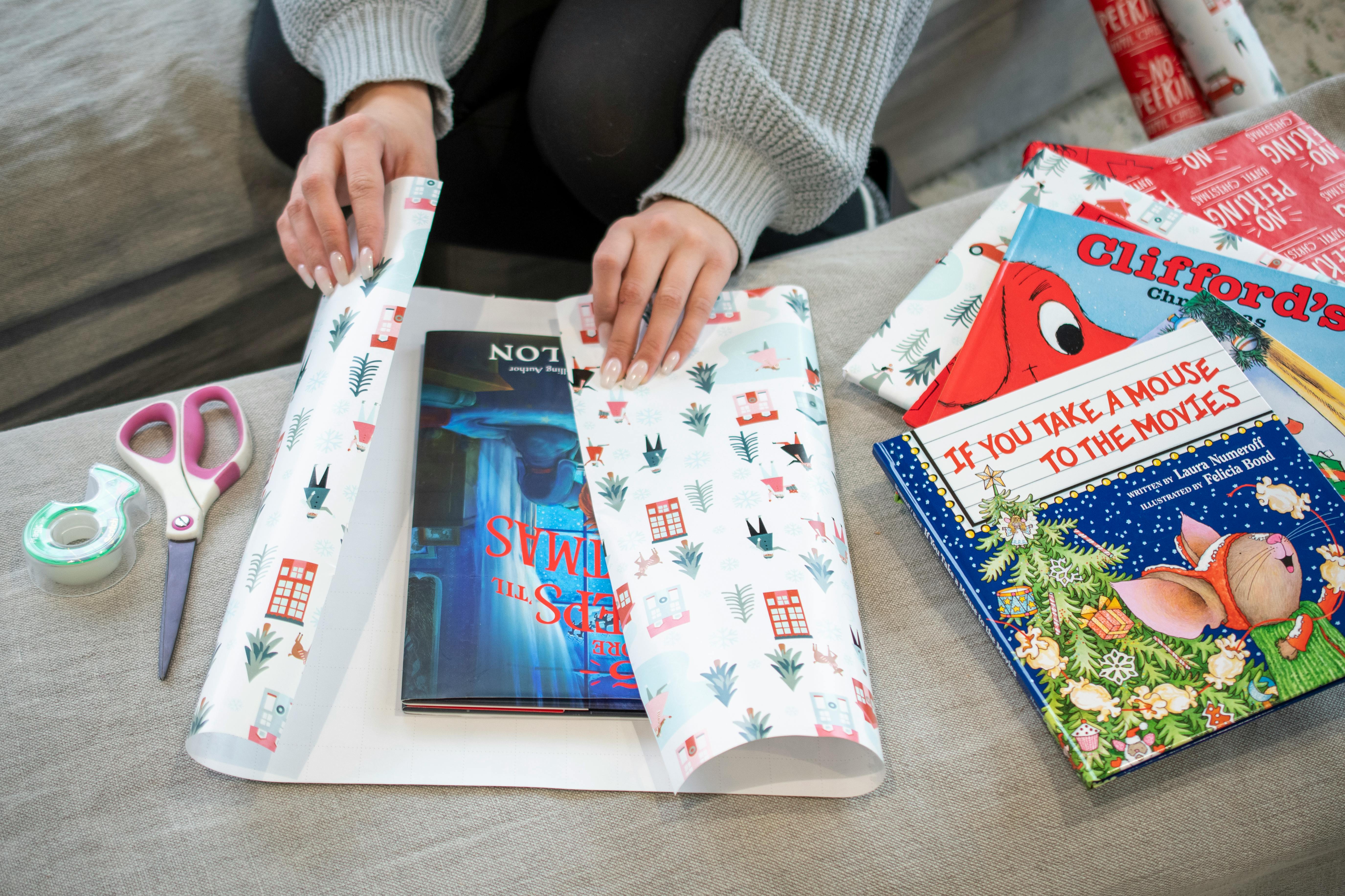 A person wrapping some books with gift wrap