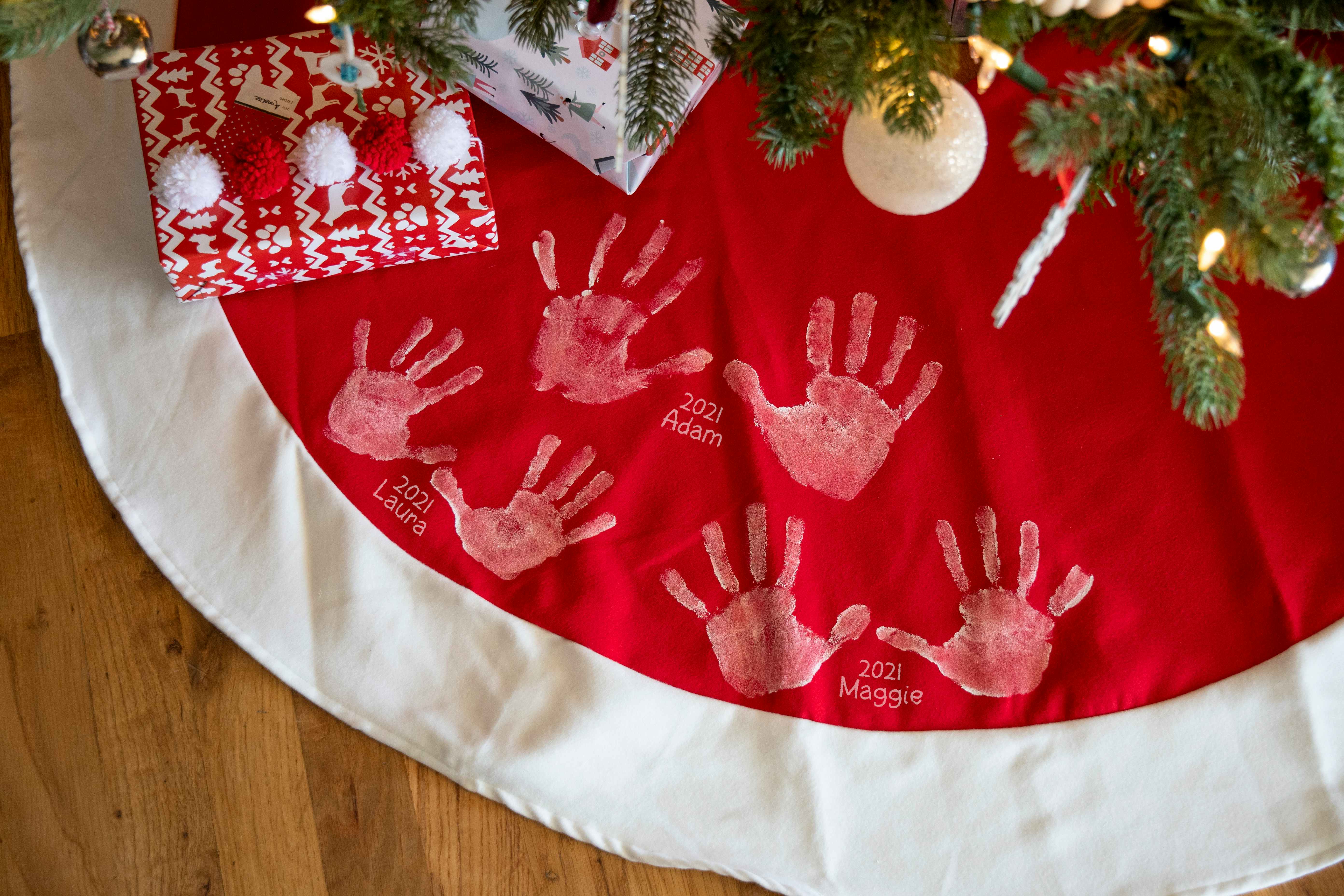 A Tree Skirt with white hand prints on it.