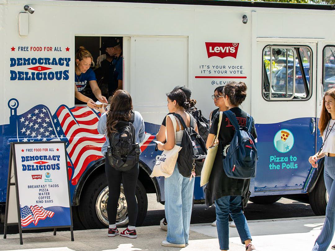 People standing in line to get a slice of pizza from the Pizza to the Polls food truck