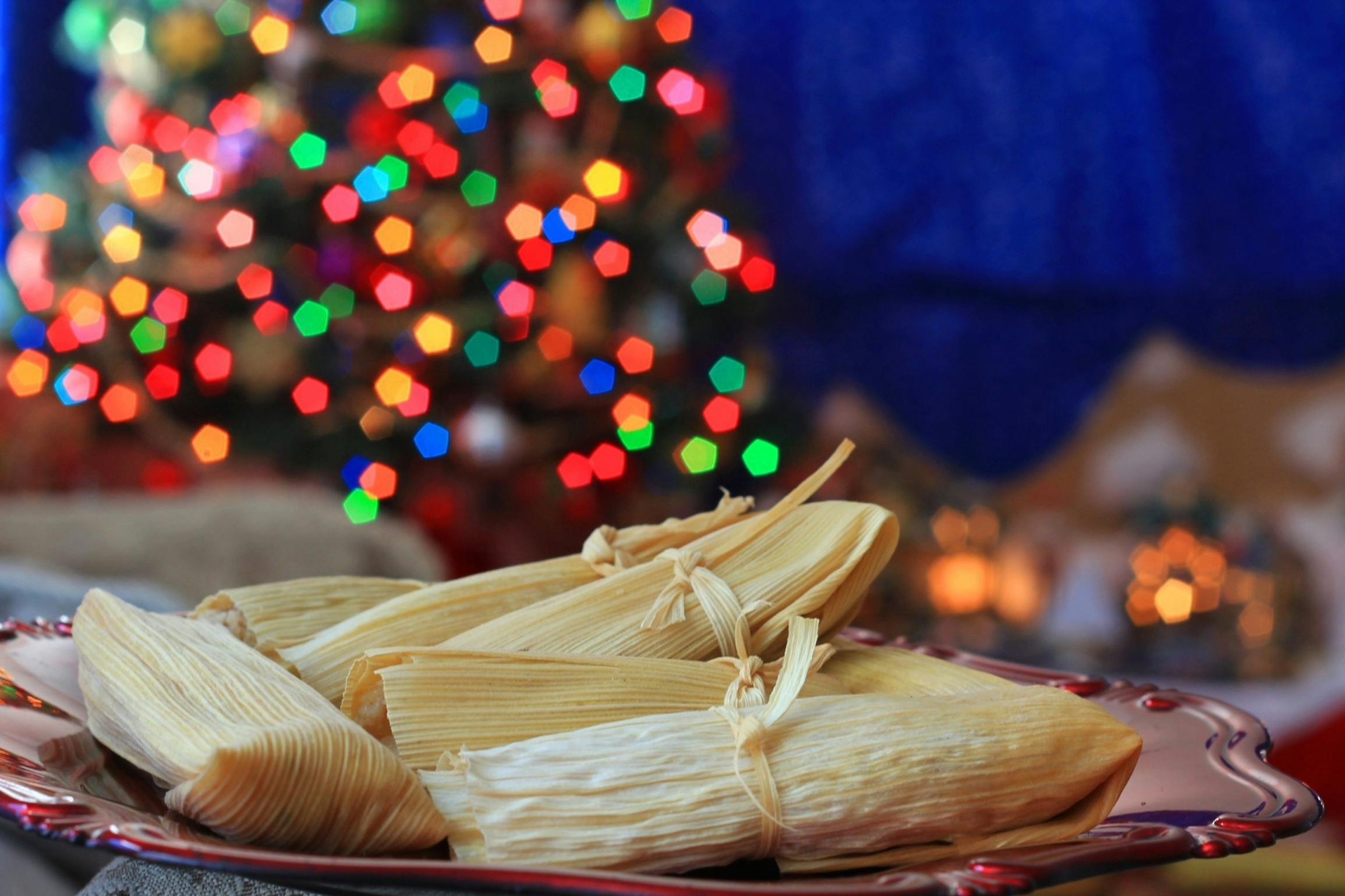 A plate of homemade tamales in front of a Christmas tree