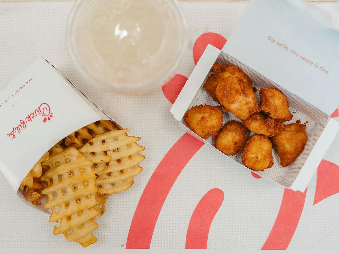 Chick-fil-A chicken nuggets on a table with waffle fries and a drink
