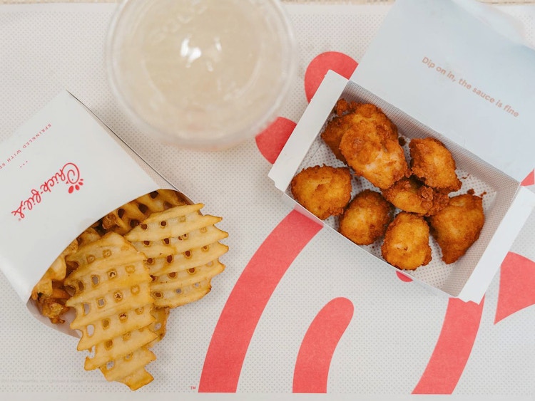 Chick-fil-A chicken nuggets on a table with waffle fries and a drink