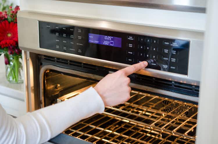 woman-pressing-button-on-oven-to-preheat